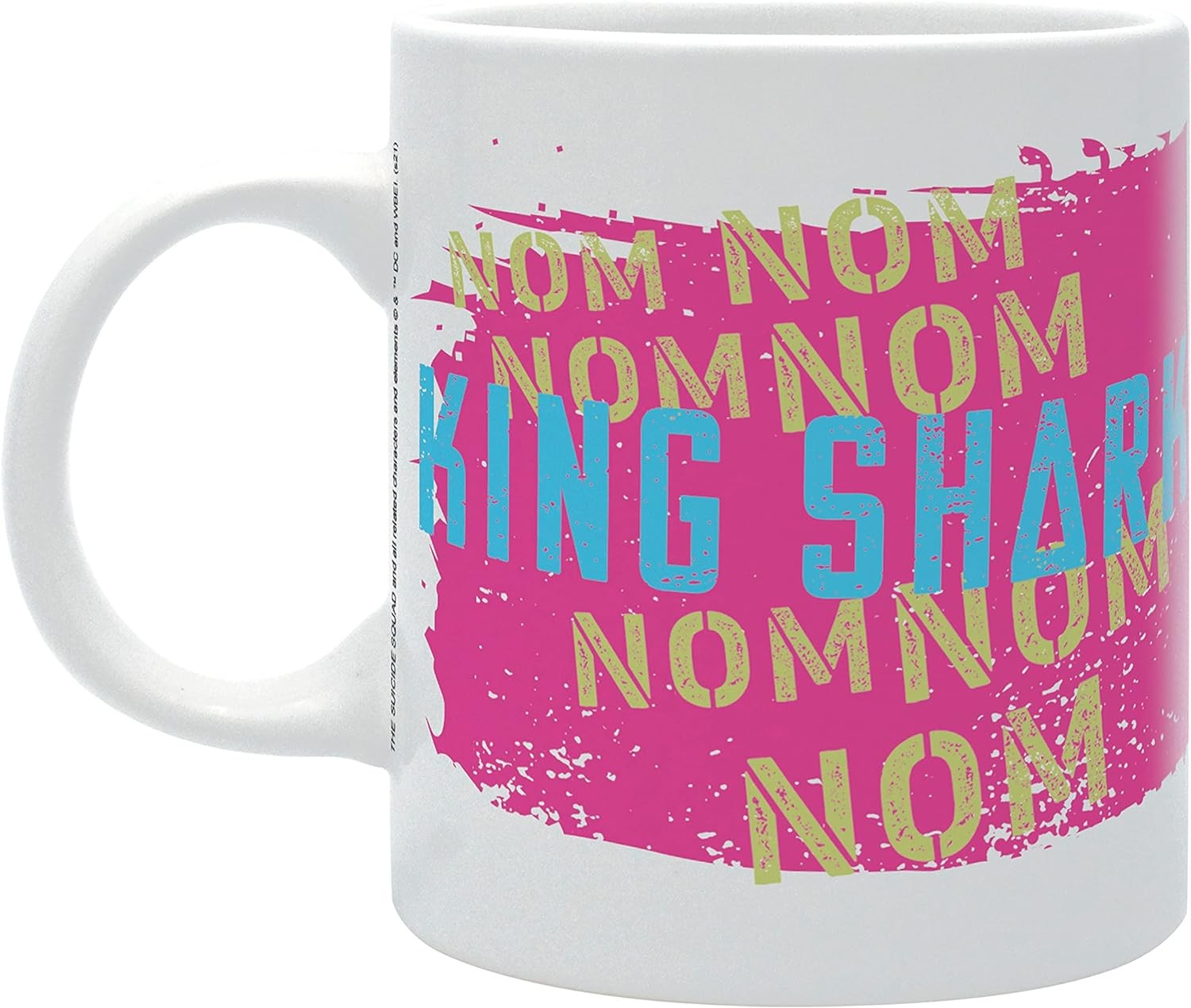 Taza blanca con salpicadura rosa y texto King Shark en verde y azul.