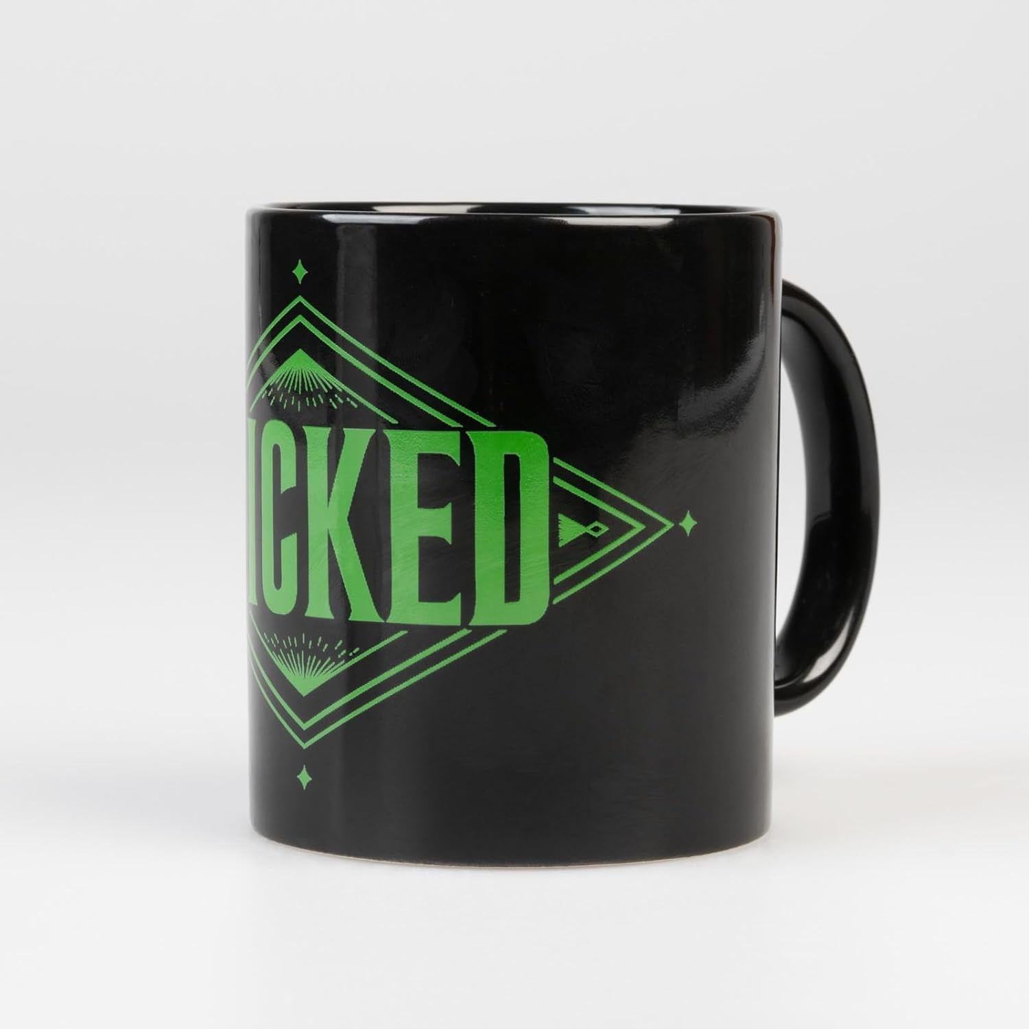 Taza de cerámica negra con letras verdes de Wicked en diseño geométrico sobre fondo blanco.