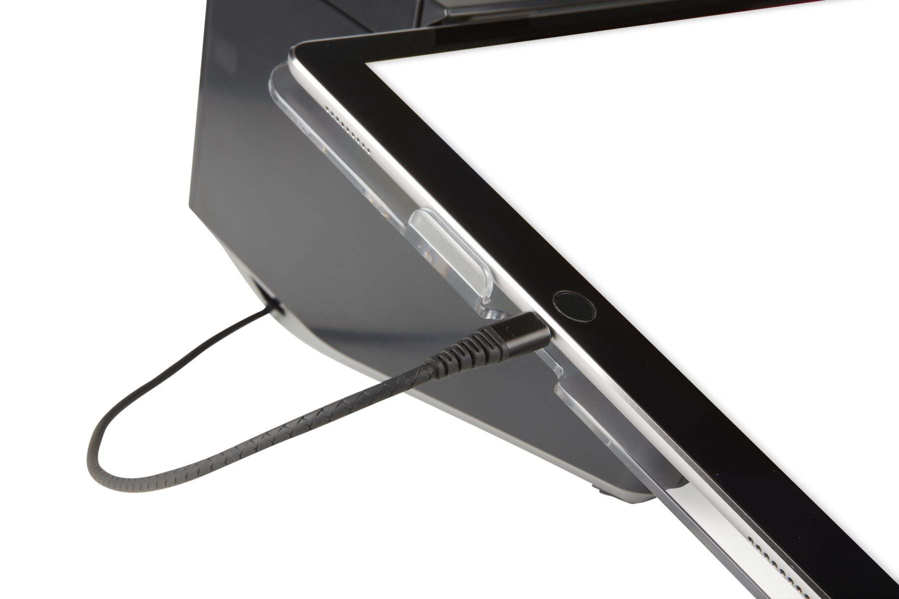 Un cable de carga negro está enchufado a un soporte para tablet sobre fondo blanco.