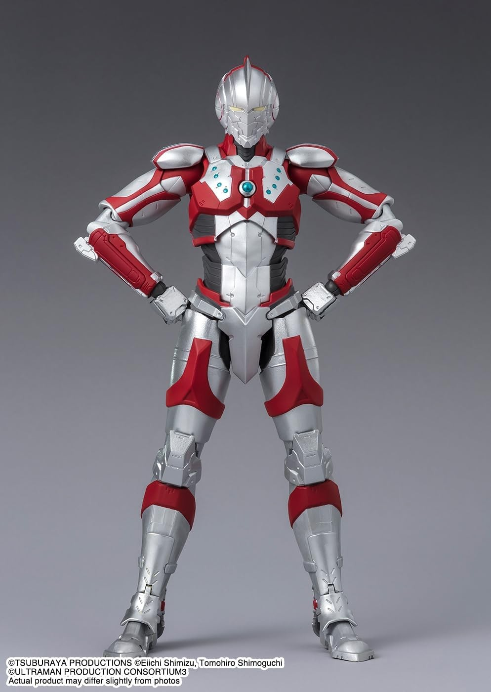 Una figura de acción roja y plateada con armadura futurista y manos en las caderas sobre fondo gris.