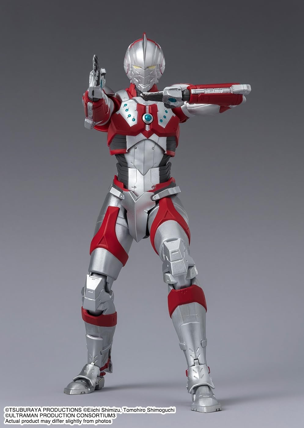 Una figura de acción de Ultraman roja y plateada posa en postura de lucha con fondo gris.