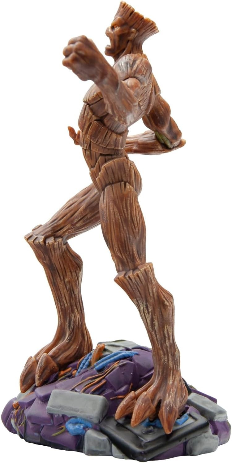 Una figura de acción parecida a un árbol con textura marrón se para sobre una base rocosa morada y gris, estirando el brazo.