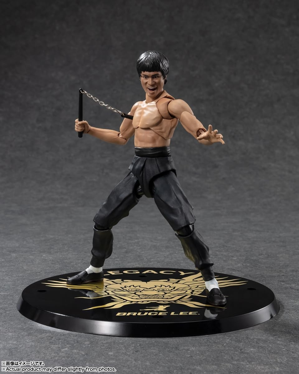 Figura de acción de Bruce Lee con nunchaku en un soporte negro con marca sobre fondo gris.