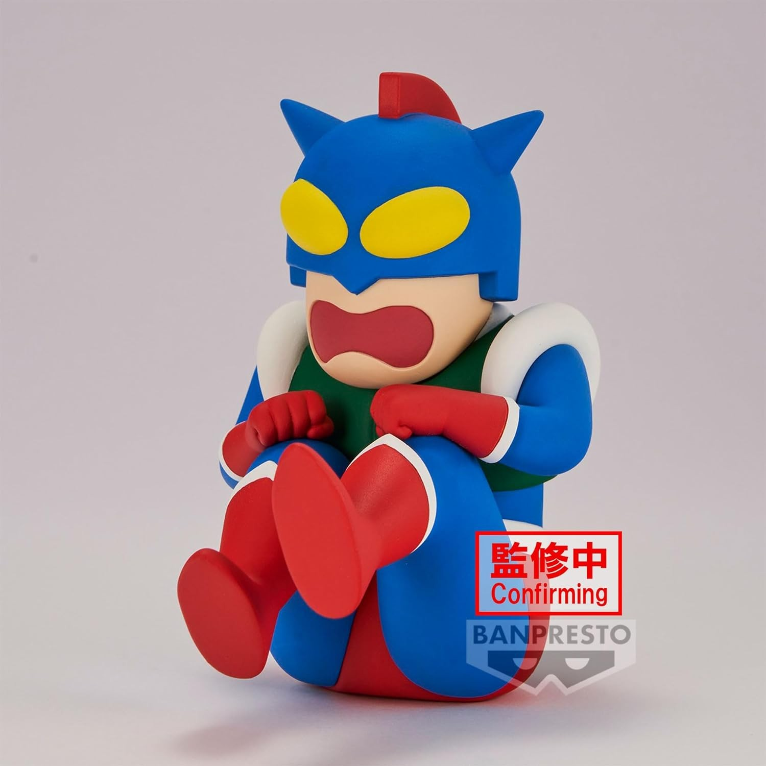 Una figura de superhéroe azul, roja y amarilla con expresión de shock está sentada.