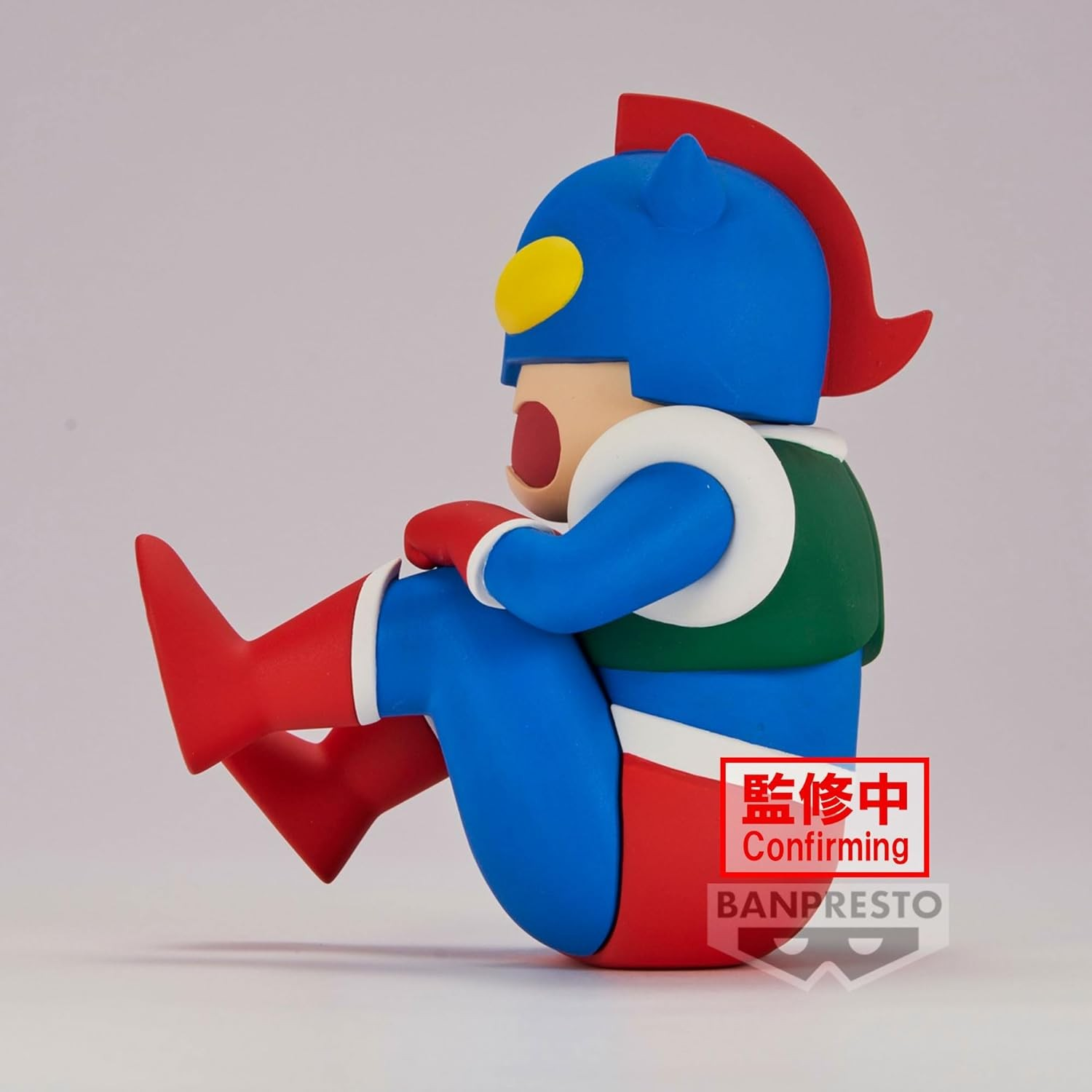 Una figura de superhéroe azul, roja y verde está sentada de perfil con las piernas dobladas.