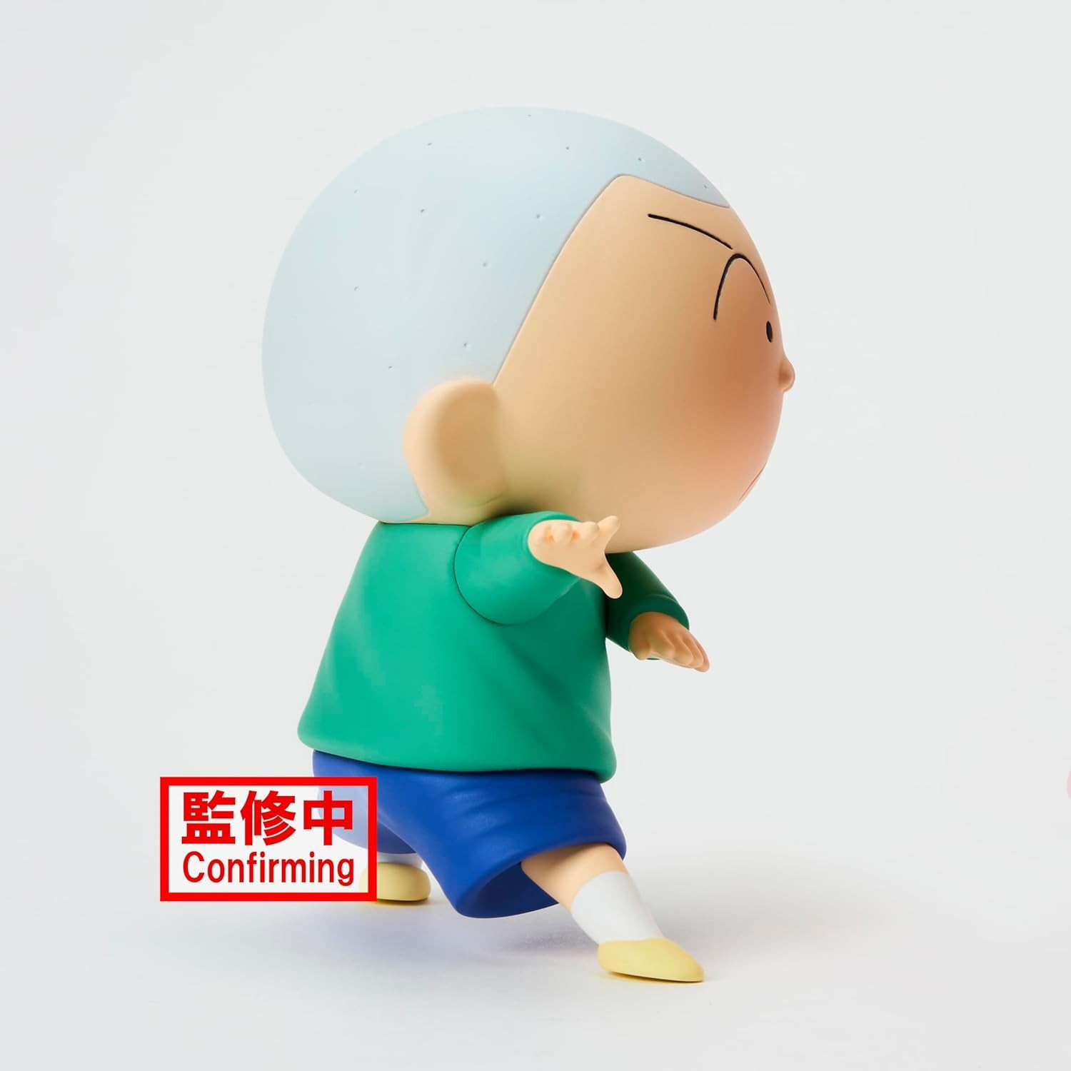 Una figura de plástico con jersey verde y pantalón azul adopta una pose de artes marciales con fondo blanco.