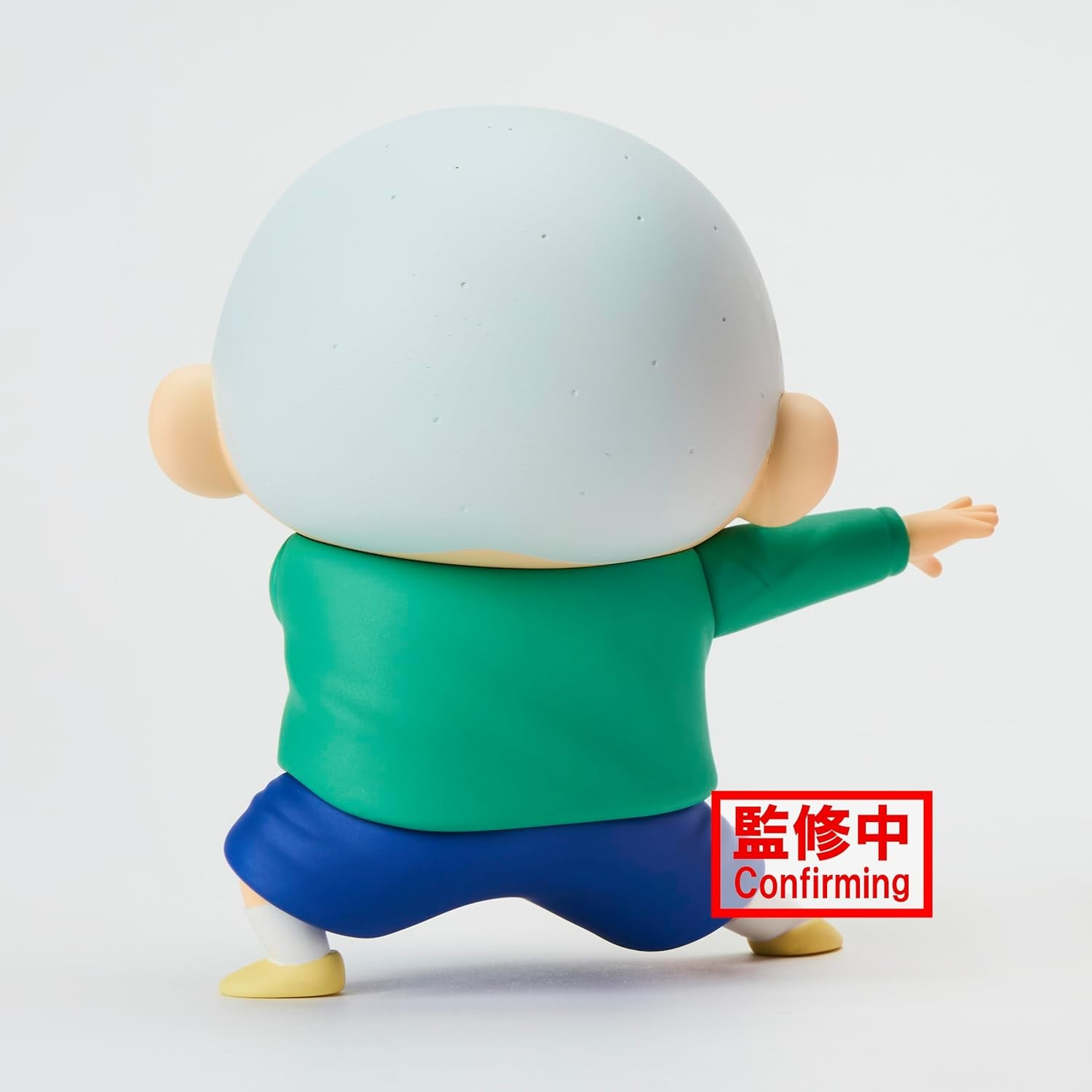 Vista trasera de una pequeña figura con cabeza calva grande, camisa verde y pantalones cortos azules, adoptando una postura.