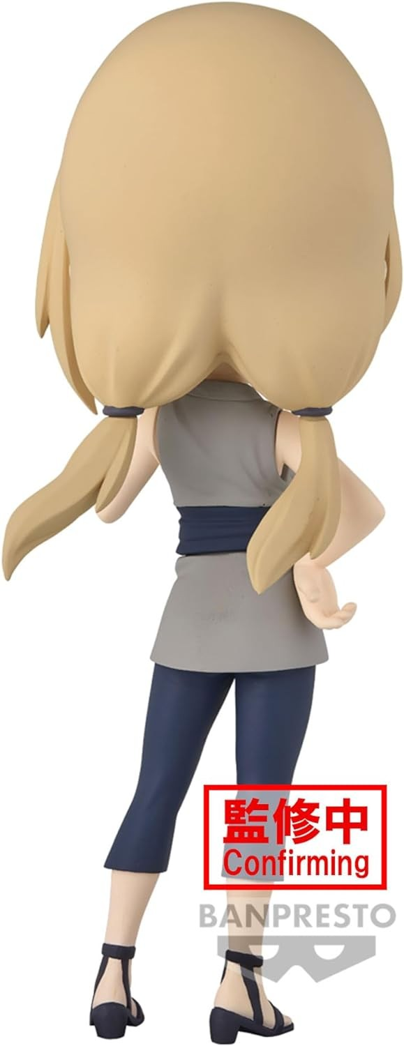 Vista trasera de una figura de anime rubia con coletas, top gris y pantalones azules sobre fondo blanco.