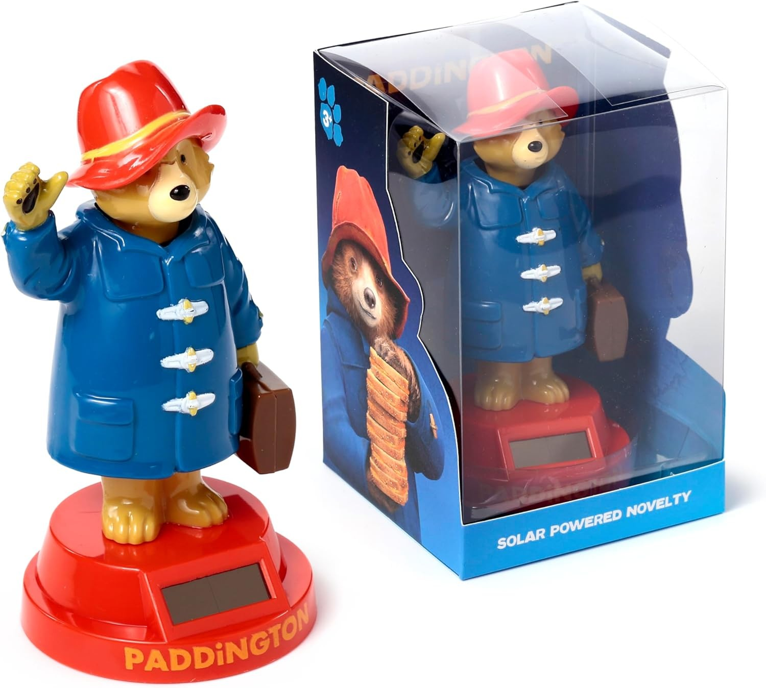Una figura del oso Paddington con abrigo azul y sombrero rojo, al lado de su caja de embalaje.
