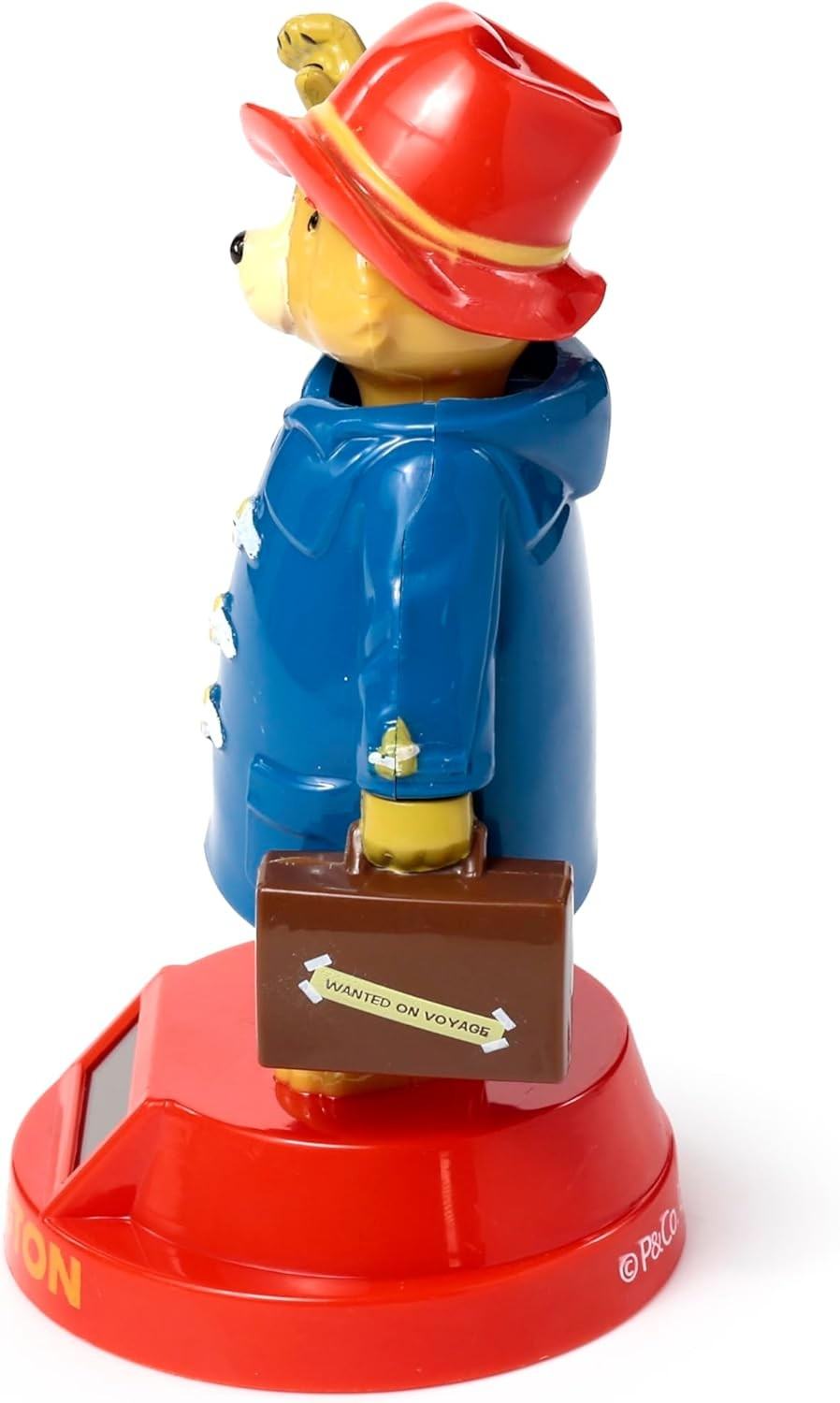 Una figura del Oso Paddington con abrigo azul, sombrero rojo y maleta marrón sobre base roja.