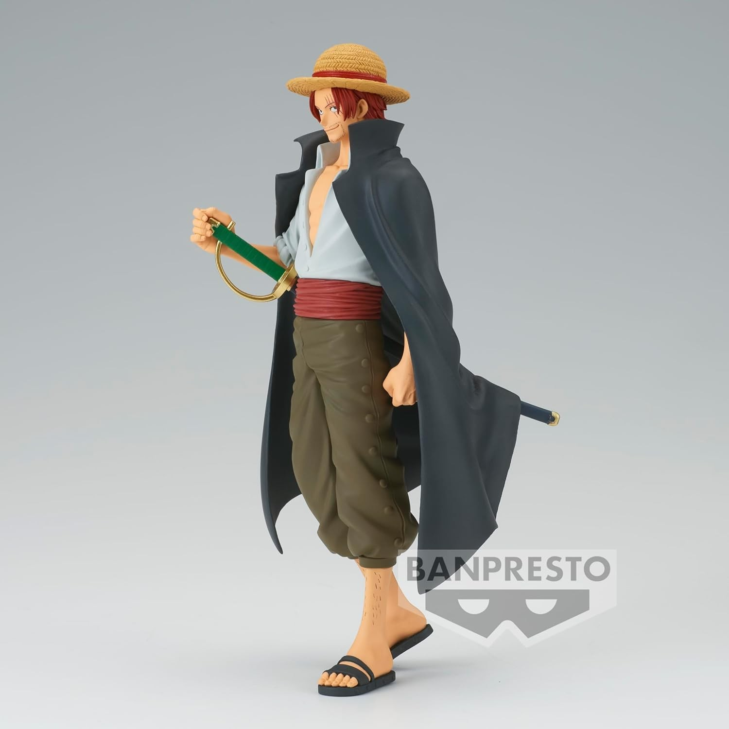 Figura de anime de Shanks con sombrero de paja, abrigo negro, espada y pantalones verdes sobre fondo gris.