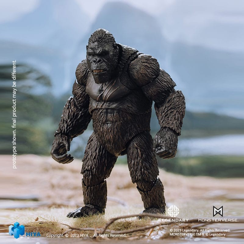 Una figura de acción detallada de King Kong de pie en una playa de arena con montañas borrosas al fondo.