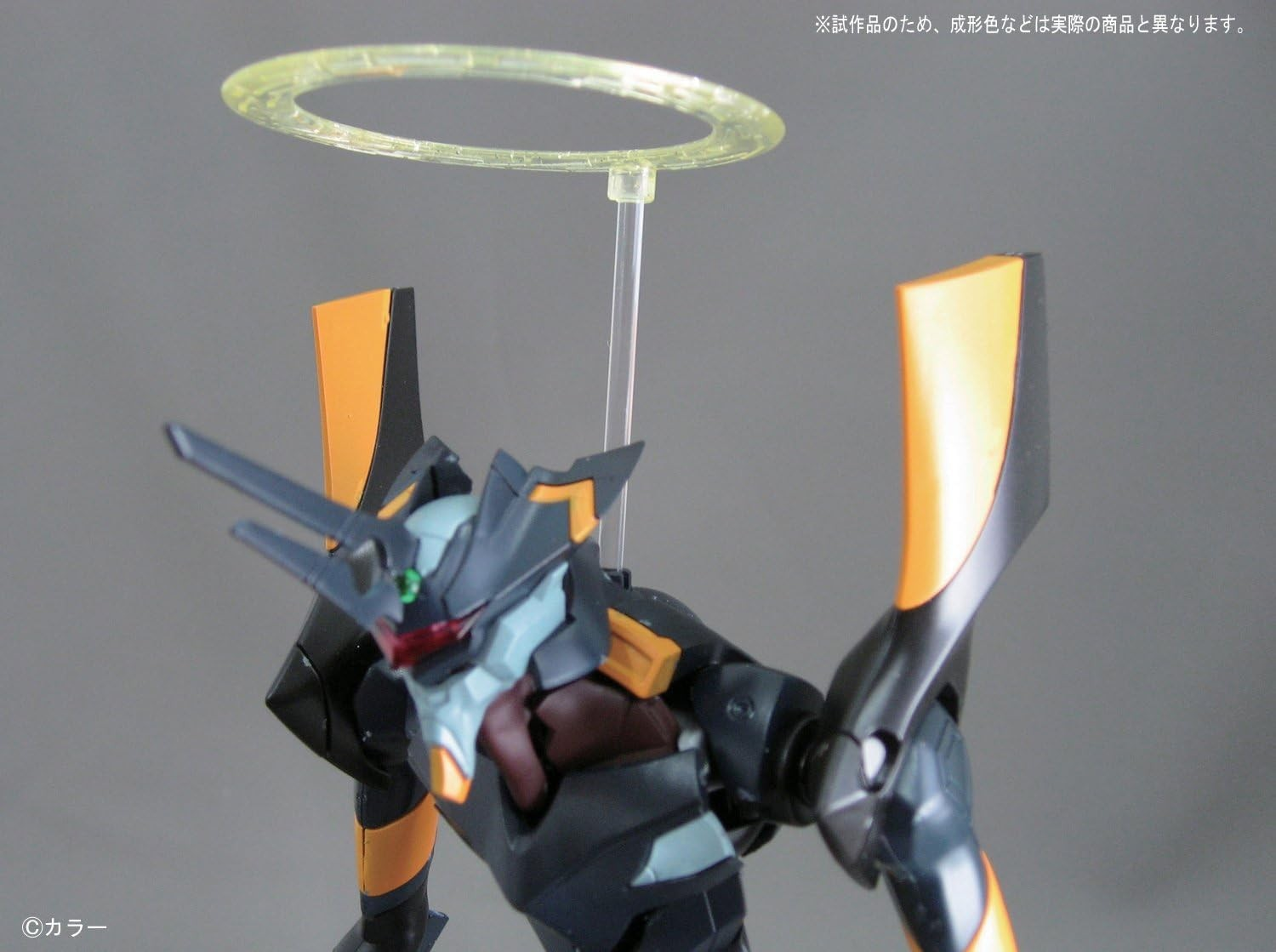 Primer plano de una figura de acción mecha negra y naranja con un halo amarillo flotando sobre su cabeza.