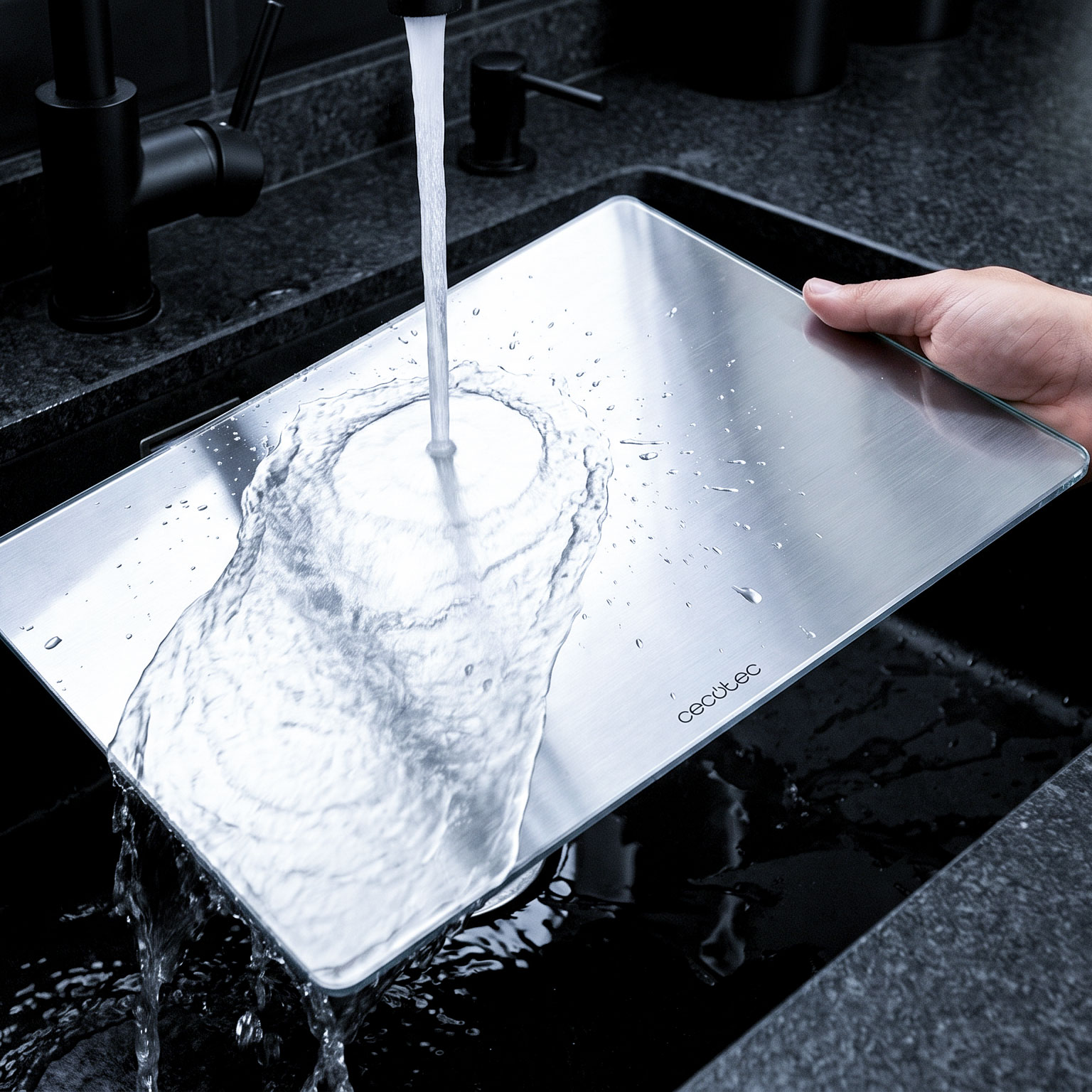 El agua corre sobre una tabla de cortar plateada en un fregadero oscuro.