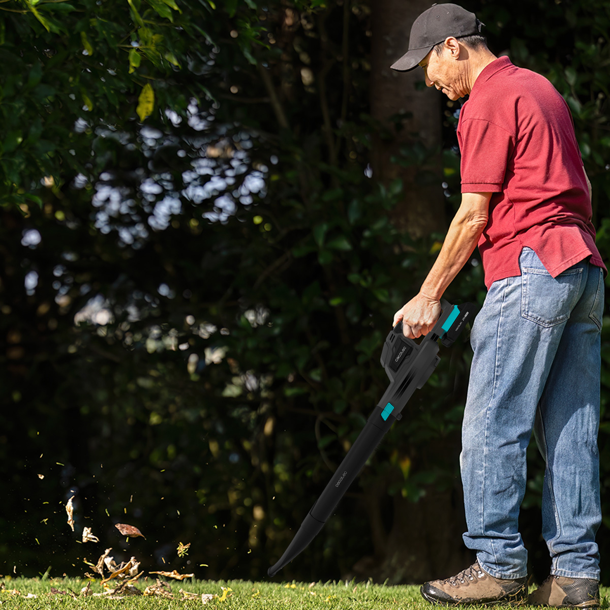 Un hombre con camisa roja y vaqueros usa un soplador de hojas en el jardín.