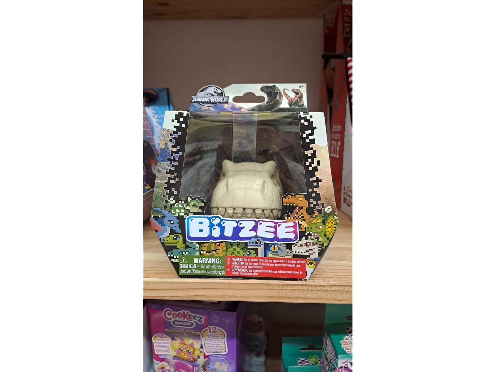 Juguete Bitzee Jurassic World en caja en un estante de madera con gráficos coloridos.