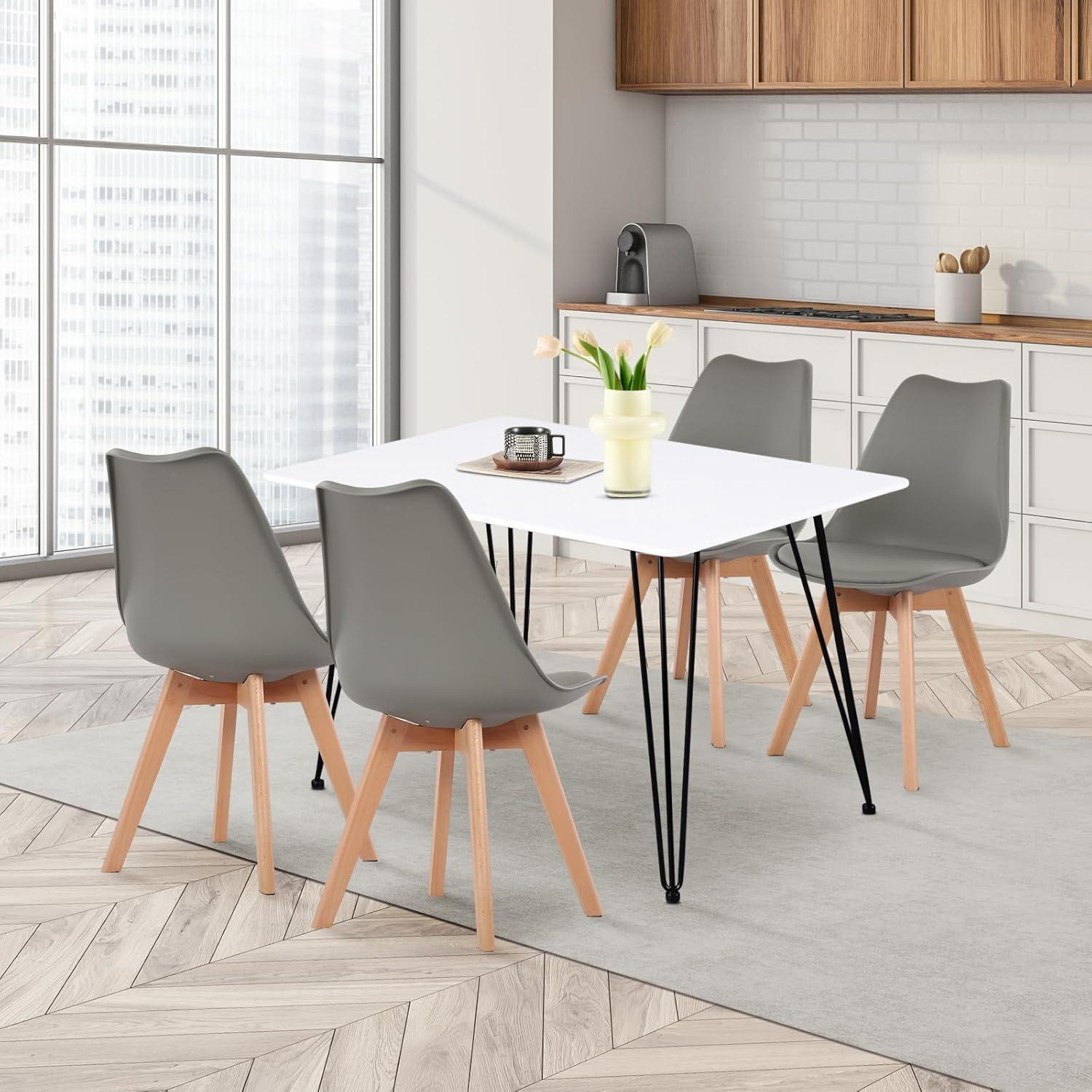 Moderno tavolo da pranzo bianco con quattro sedie grigie e gambe in legno in una cucina luminosa.