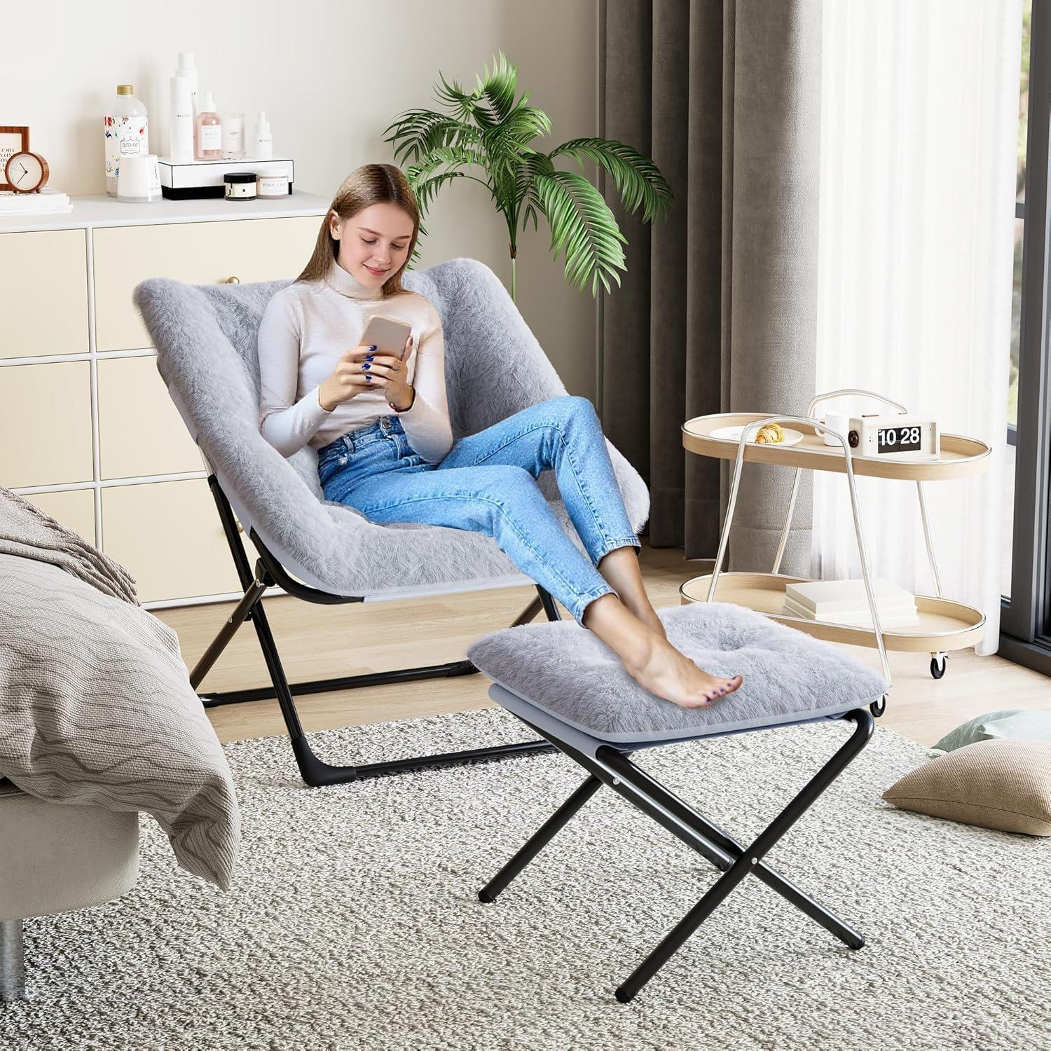 Una donna siede su una poltrona di peluche grigia usando lo smartphone, con i piedi poggiati su uno sgabello coordinato.