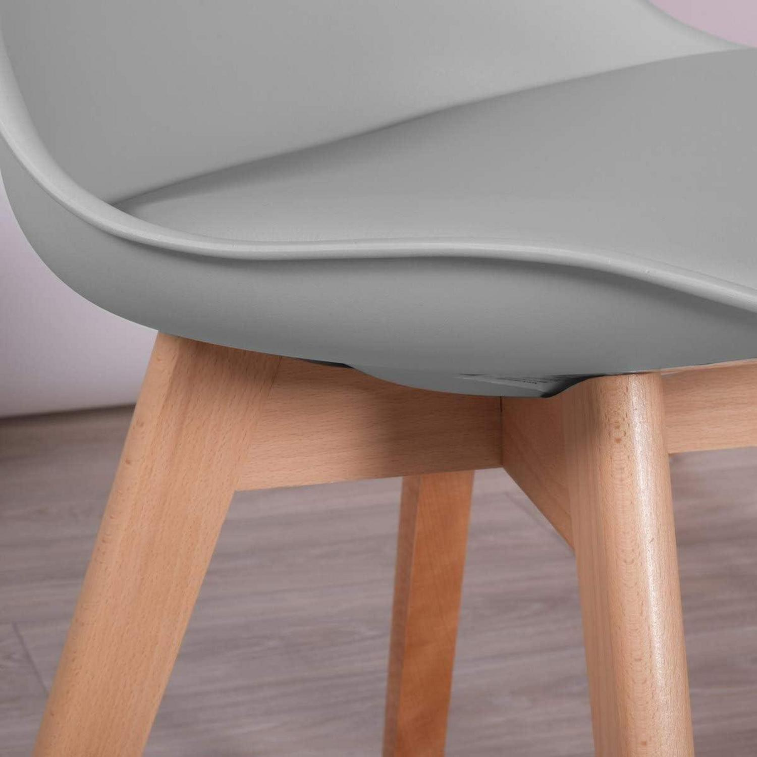 Una sedia in plastica grigia con gambe in legno chiaro su pavimento in legno.