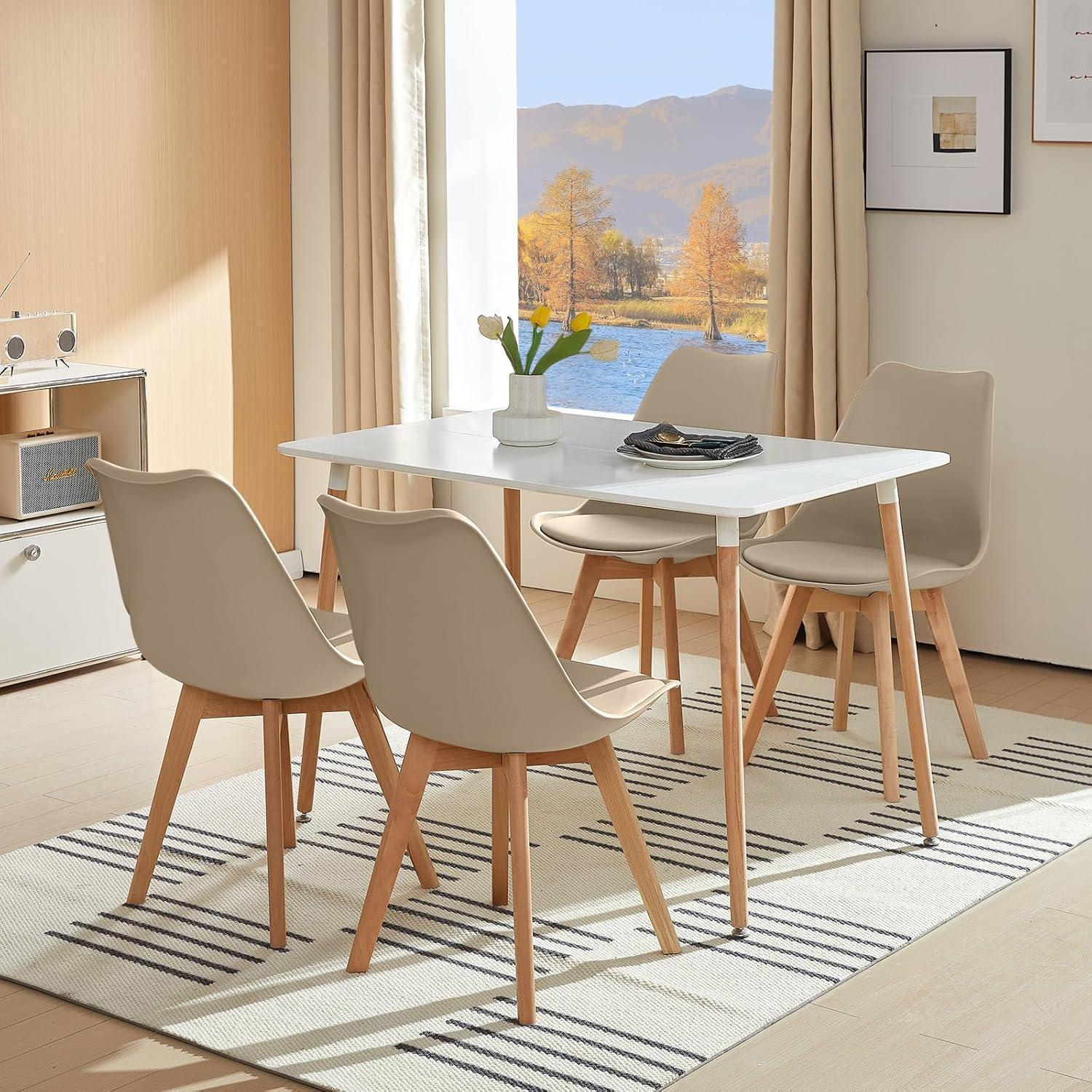 Moderno tavolo da pranzo bianco con quattro sedie beige su tappeto fantasia davanti a una finestra con vista.