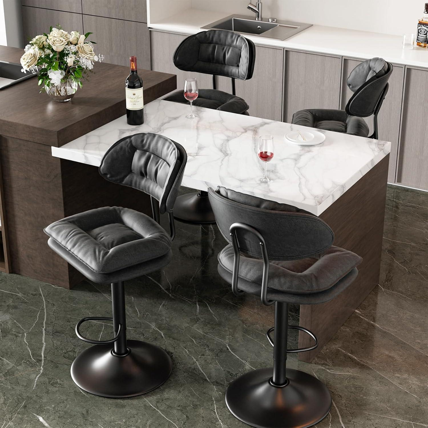 Isola cucina moderna con piano in marmo bianco, quattro sgabelli neri, bicchieri di vino e bottiglia.