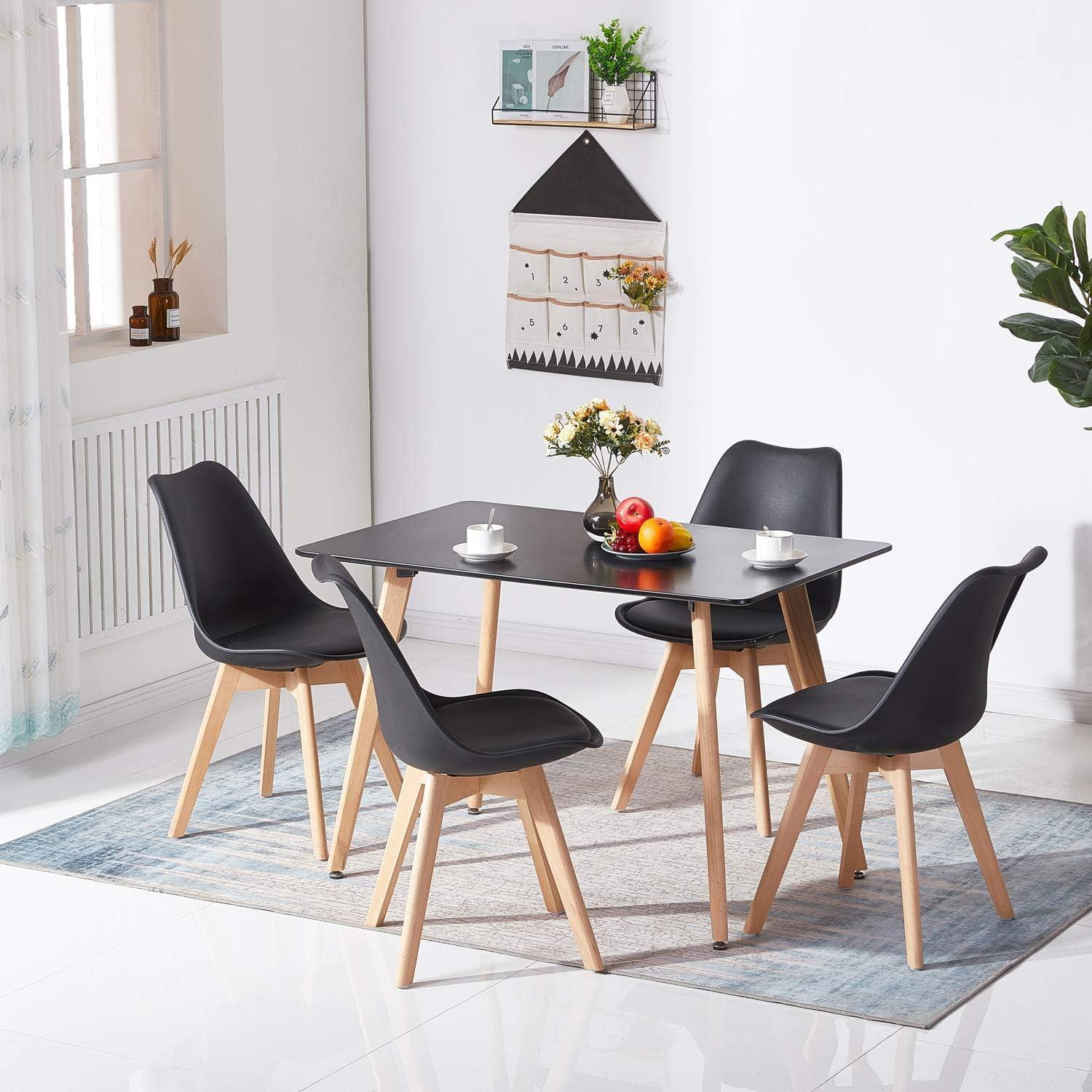 Moderno tavolo da pranzo nero con quattro sedie in legno e nere su un tappeto blu in una stanza luminosa.