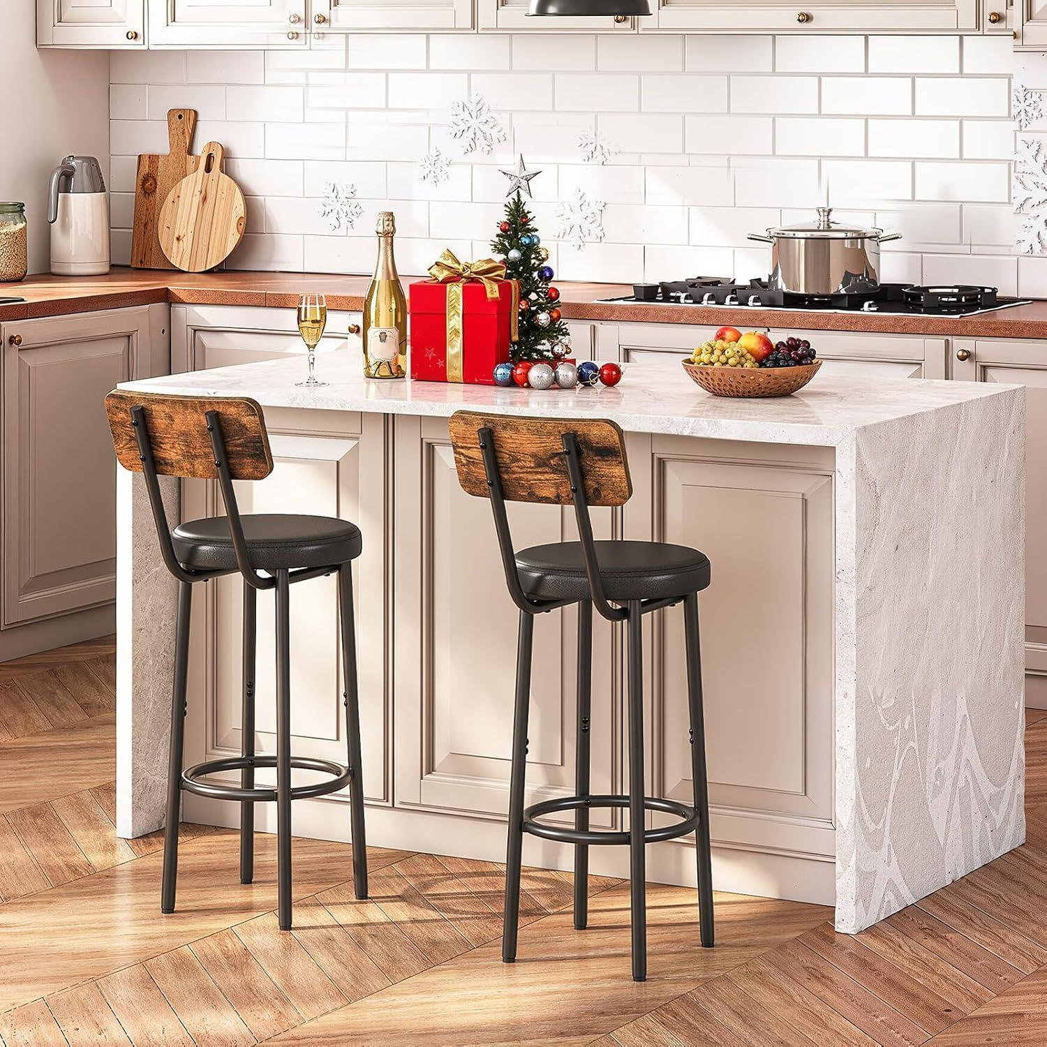 Due sgabelli da bar accanto a un'isola cucina in marmo decorata per Natale.