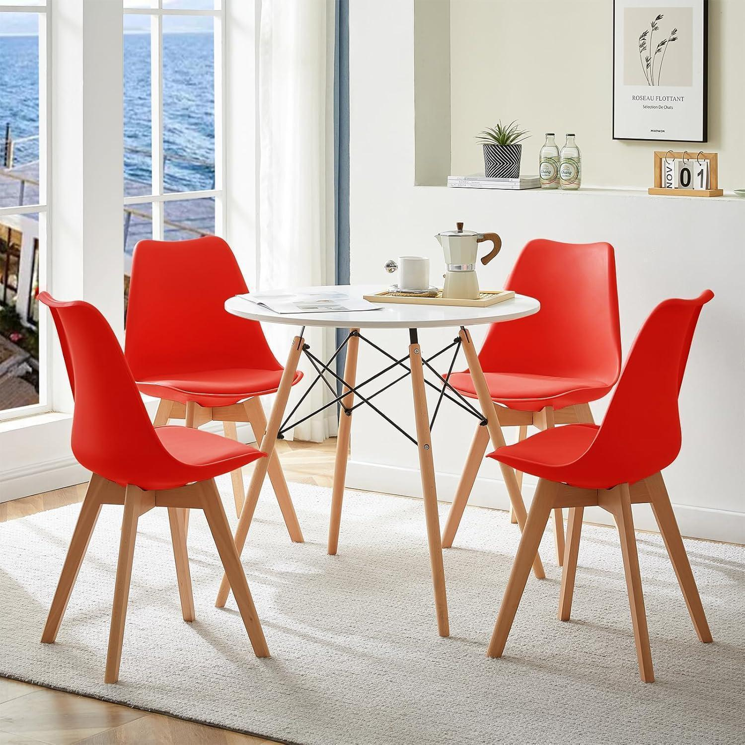 Un tavolo rotondo bianco con quattro sedie rosse e gambe di legno su un tappeto davanti a una grande finestra.