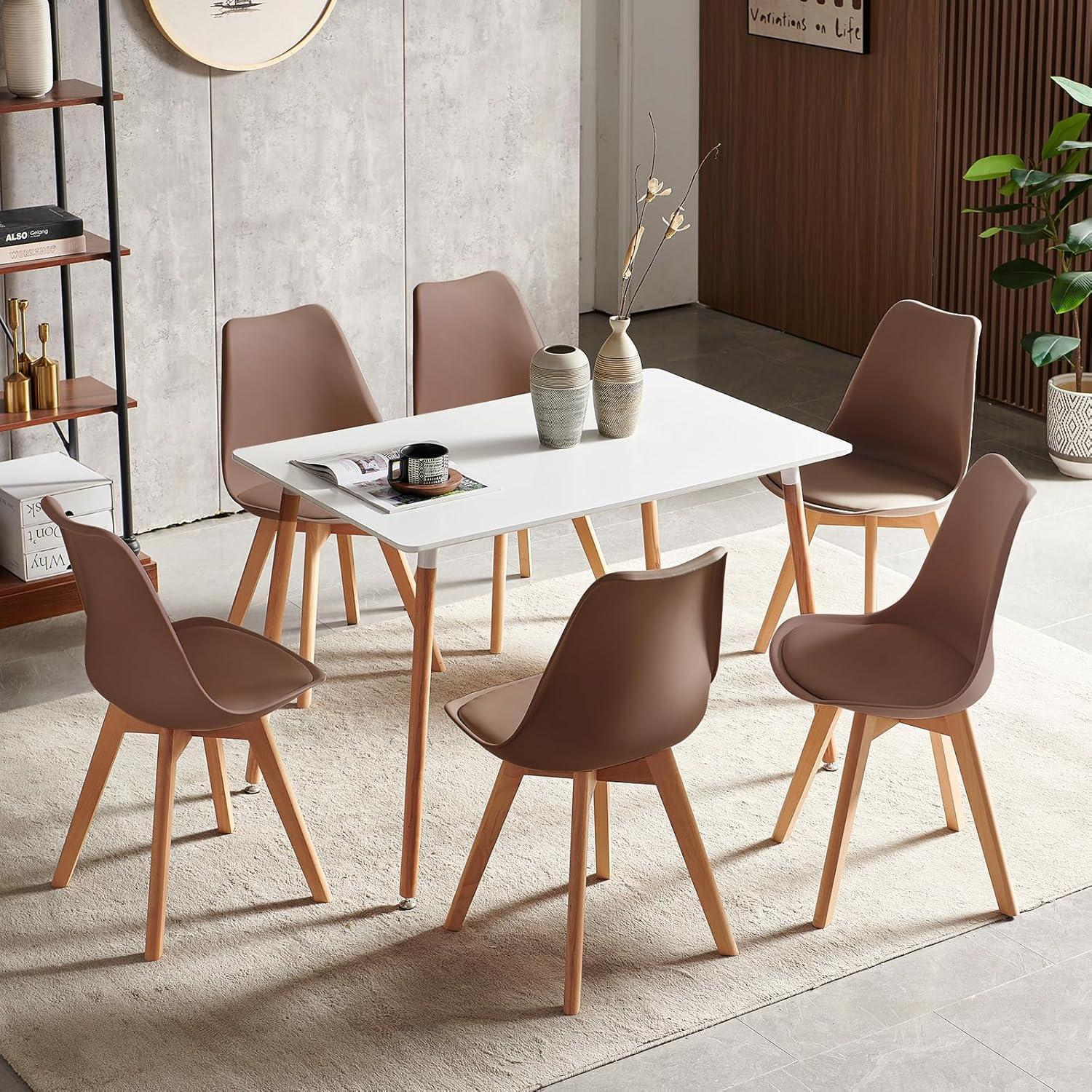 Un tavolo da pranzo bianco con sei sedie marroni e gambe in legno si trova su un tappeto in una stanza moderna.