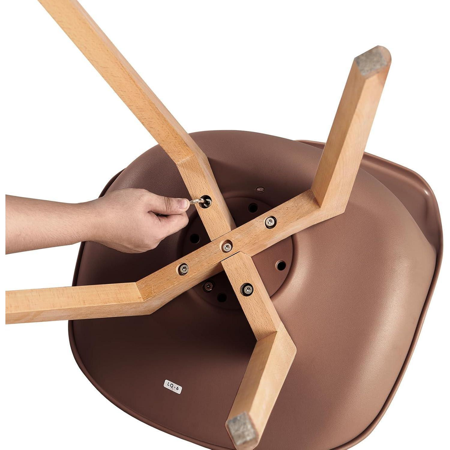 Una mano usa una chiave a brugola per stringere una vite sulle gambe di legno di una sedia marrone.