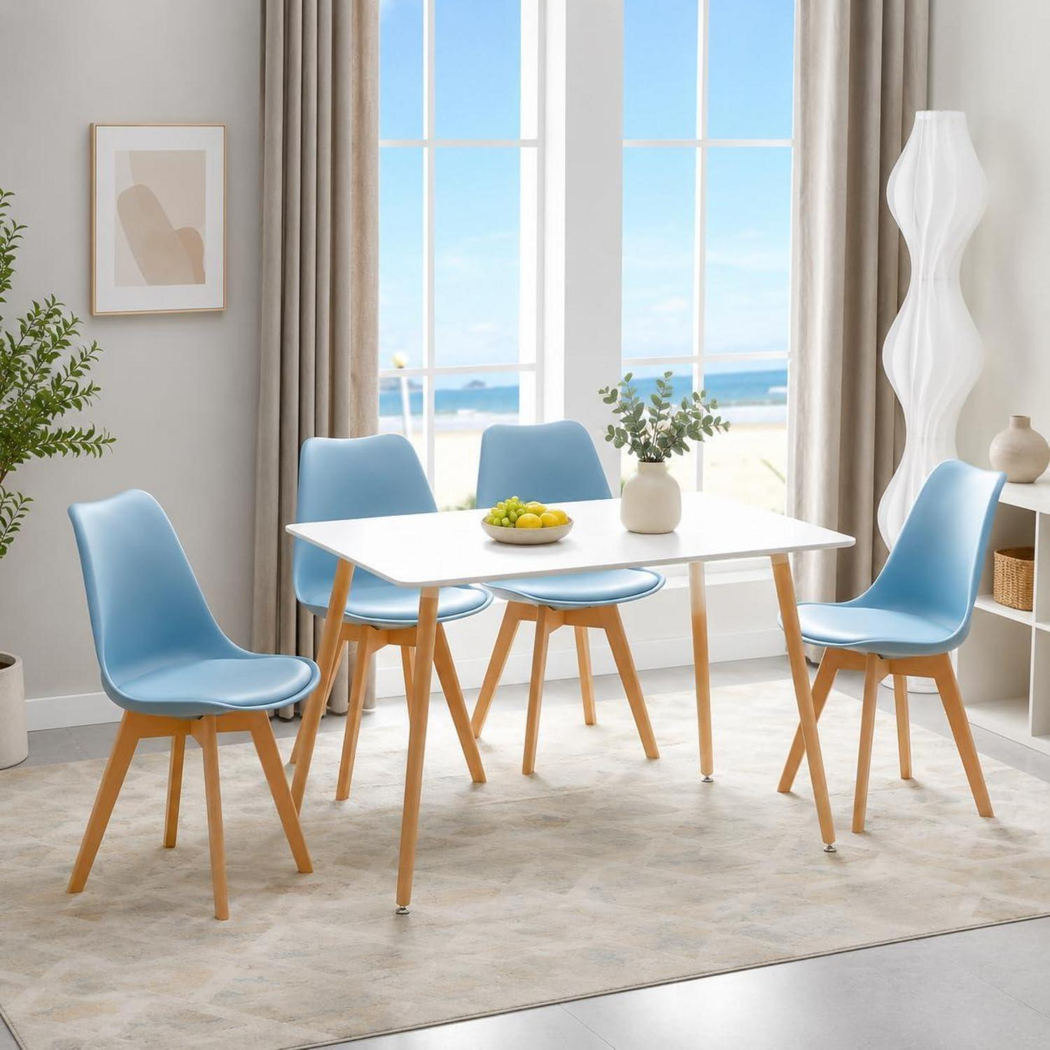 Un tavolo da pranzo bianco con quattro sedie blu, gambe in legno e frutta su un tappeto, con vista sulla costa.