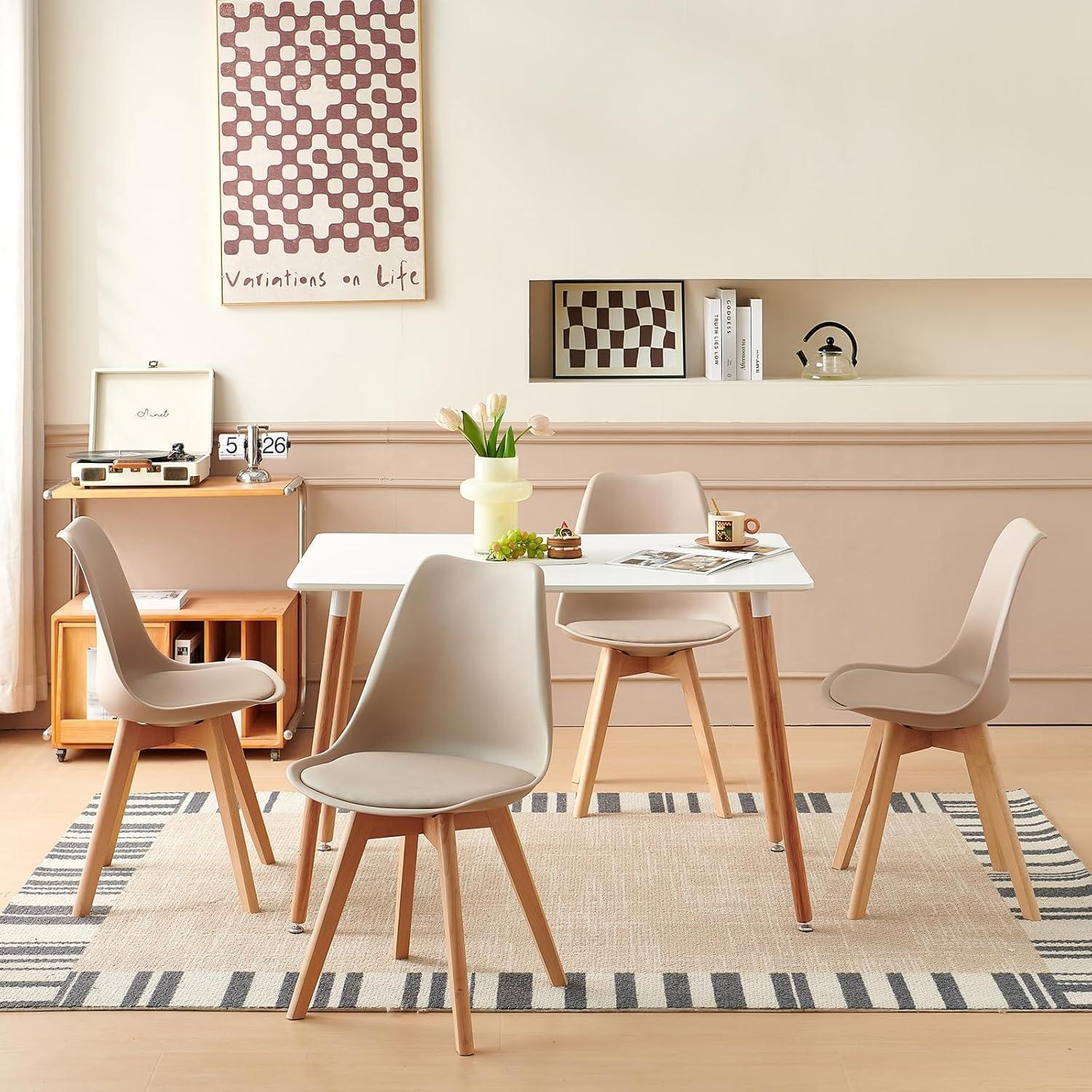 Moderno set da pranzo con tavolo bianco e quattro sedie beige su tappeto a righe in una stanza luminosa.