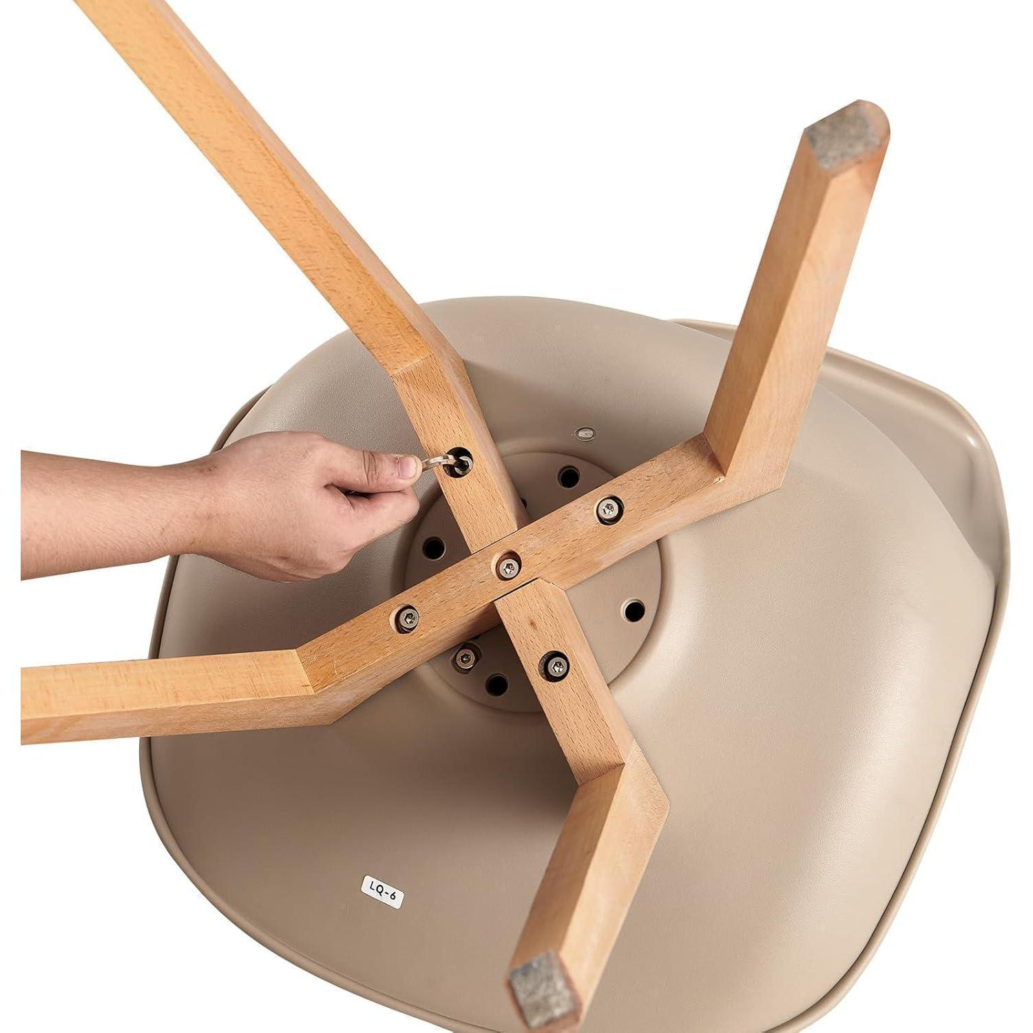 Una mano avvita le gambe in legno di una sedia su una scocca in plastica beige.