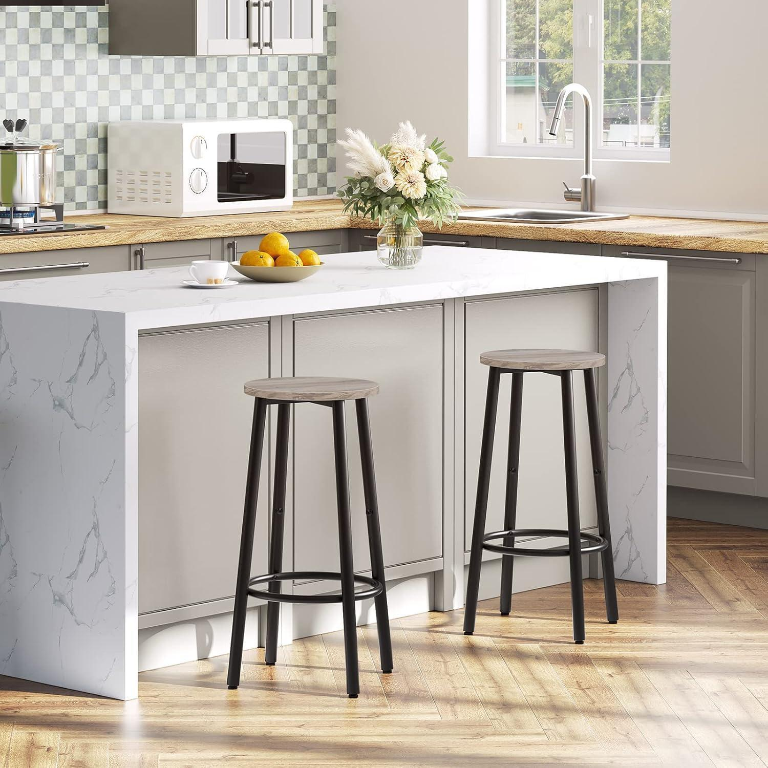 Cucina moderna con isola in marmo bianco, due sgabelli da bar, pavimenti in legno e paraschizzi a piastrelle verde e bianche.