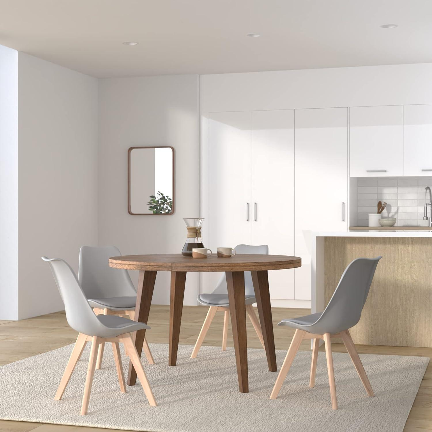 Un tavolo da pranzo rotondo in legno con quattro sedie grigie si trova su un tappeto in una cucina moderna.
