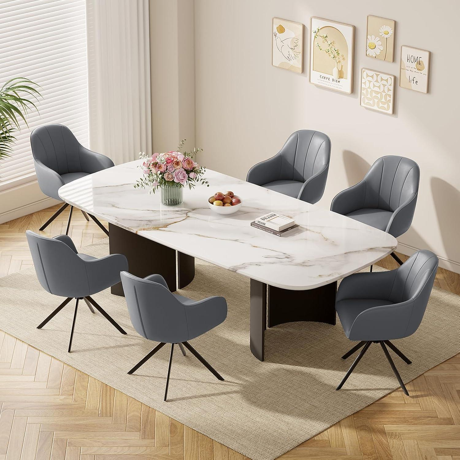 Sala da pranzo con tavolo in marmo bianco, sei poltroncine grigie e quadri.
