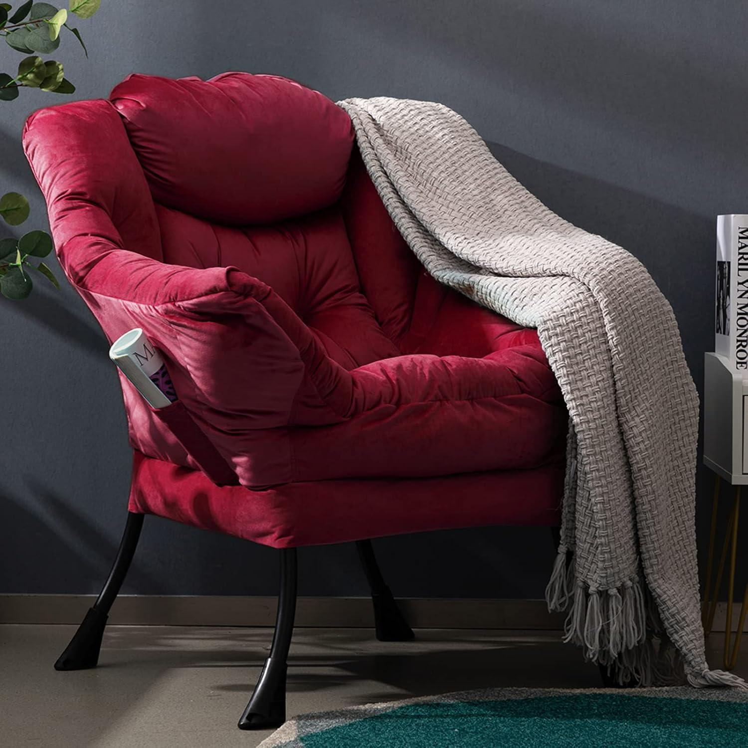 Una poltrona di peluche rossa con gambe nere, una coperta grigia e una rivista nella tasca laterale.