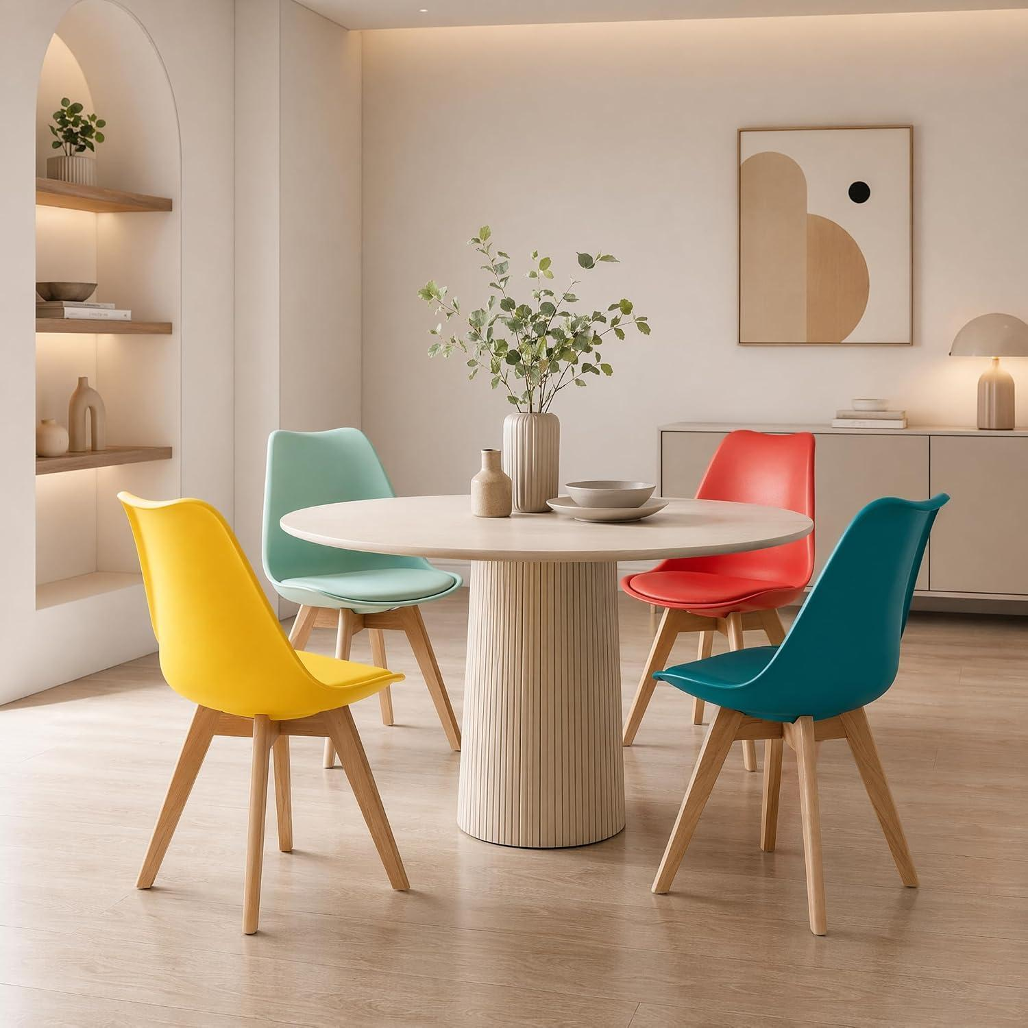 Un tavolo da pranzo rotondo bianco con quattro sedie colorate in giallo, verde acqua, rosso e verde menta.