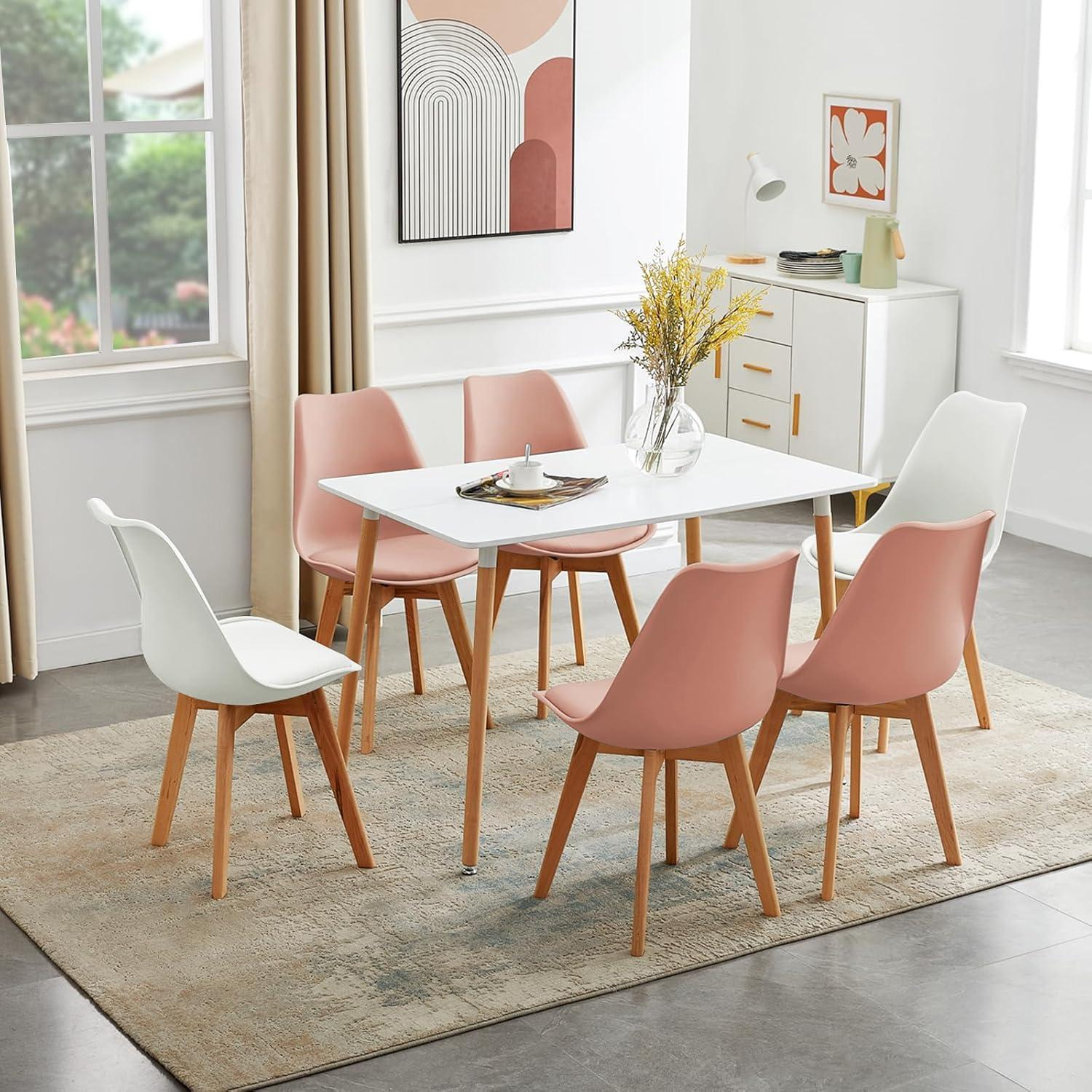 Moderna zona pranzo con tavolo bianco e sedie rosa e bianche su tappeto fantasia.