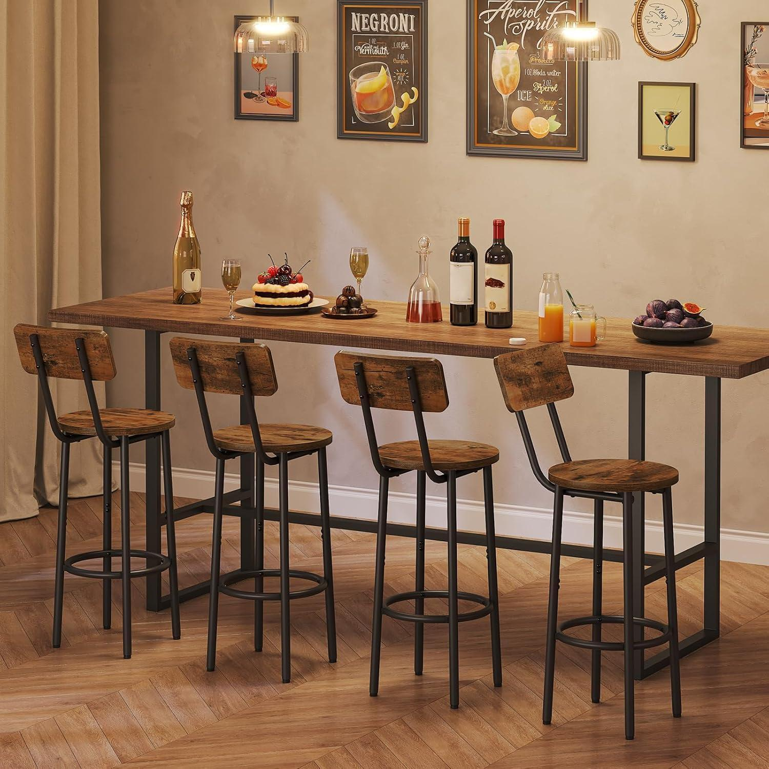 Lungo tavolo in legno con quattro sgabelli, bevande e dolci, davanti a una parete beige.