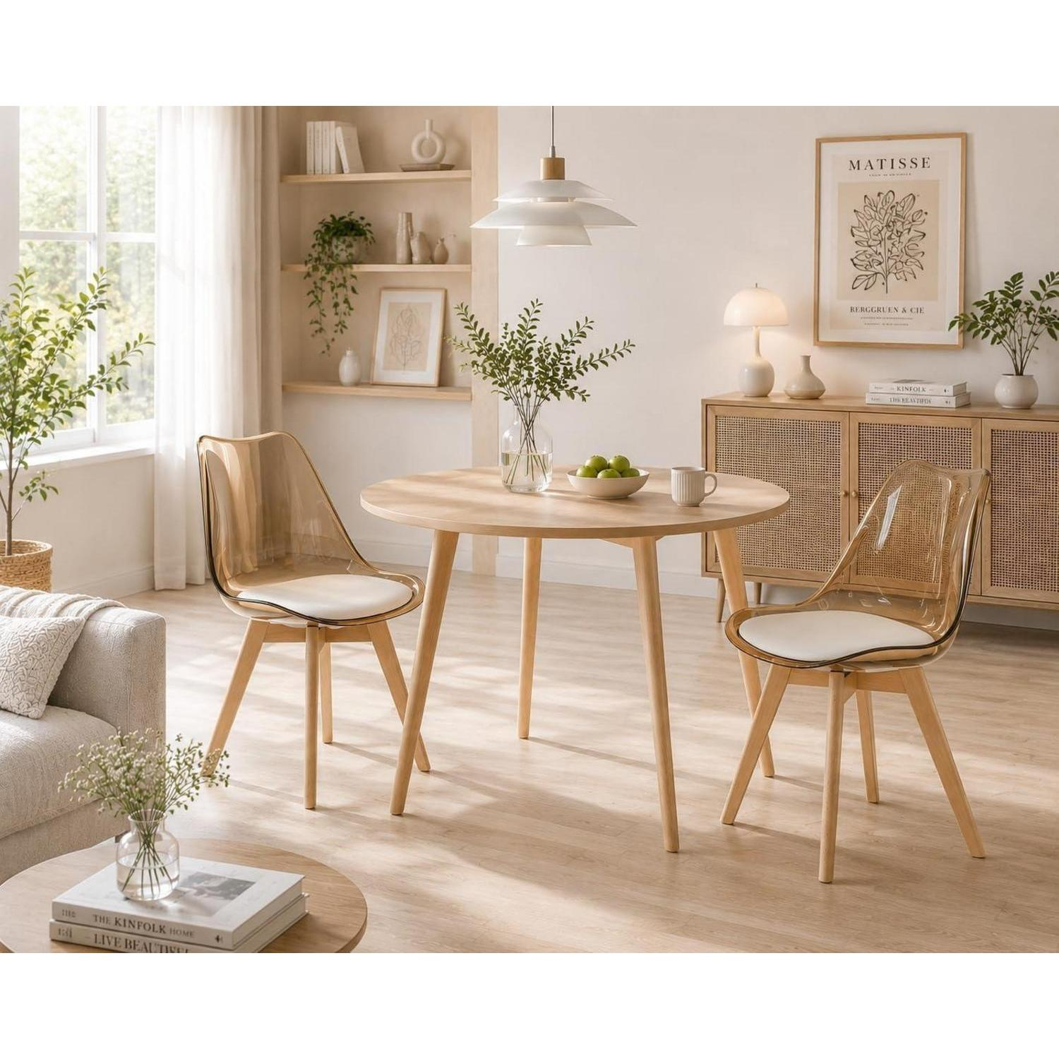 Una luminosa zona pranzo con un tavolo rotondo in legno e due sedie trasparenti.