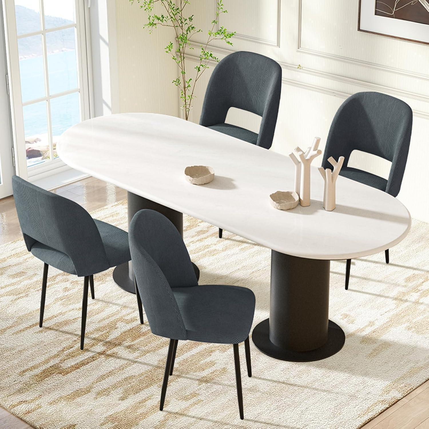 Un tavolo da pranzo ovale bianco con quattro sedie grigio scuro su un tappeto beige in una stanza luminosa.