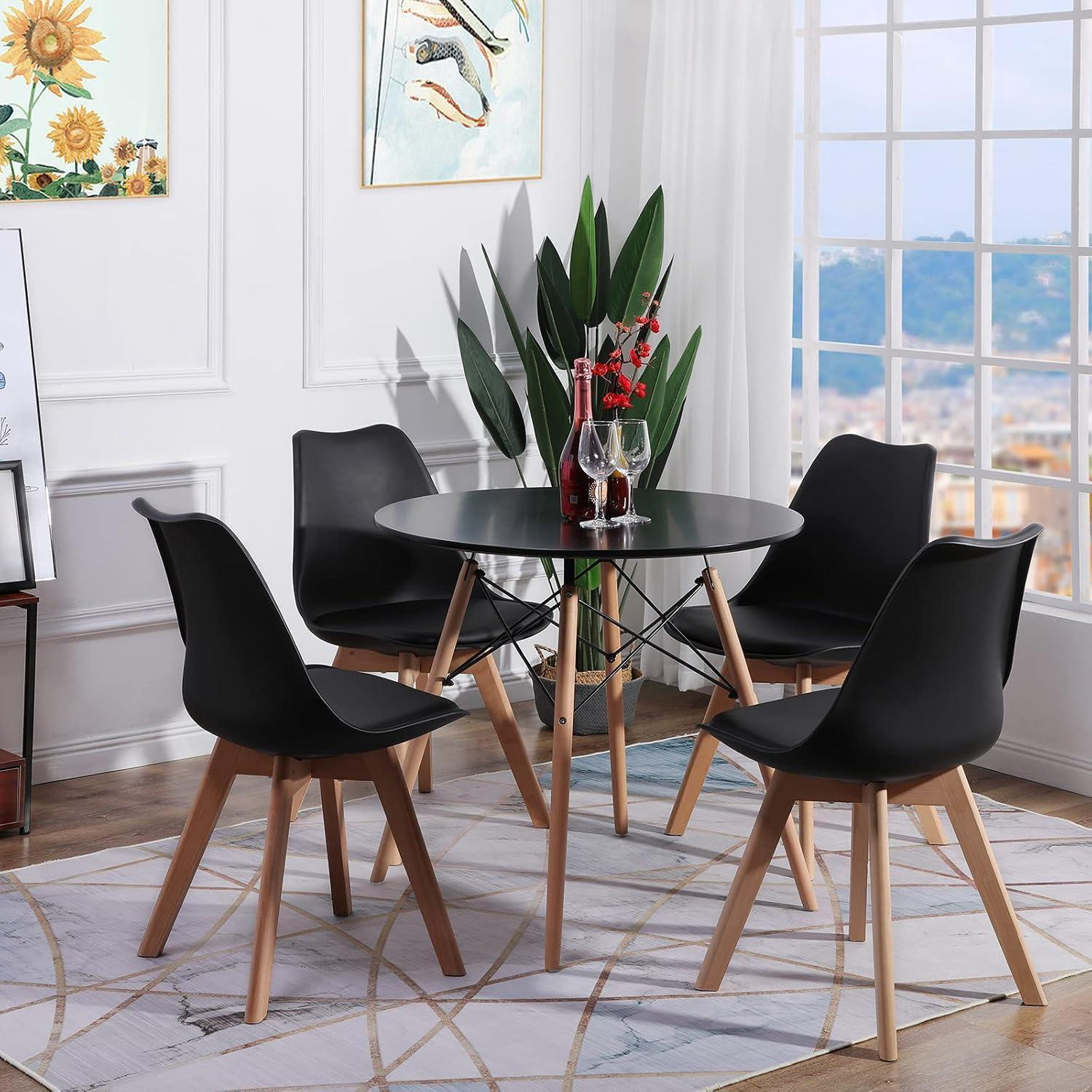 Un tavolo da pranzo rotondo nero con quattro sedie nere su un tappeto fantasia, con una grande finestra sullo sfondo.