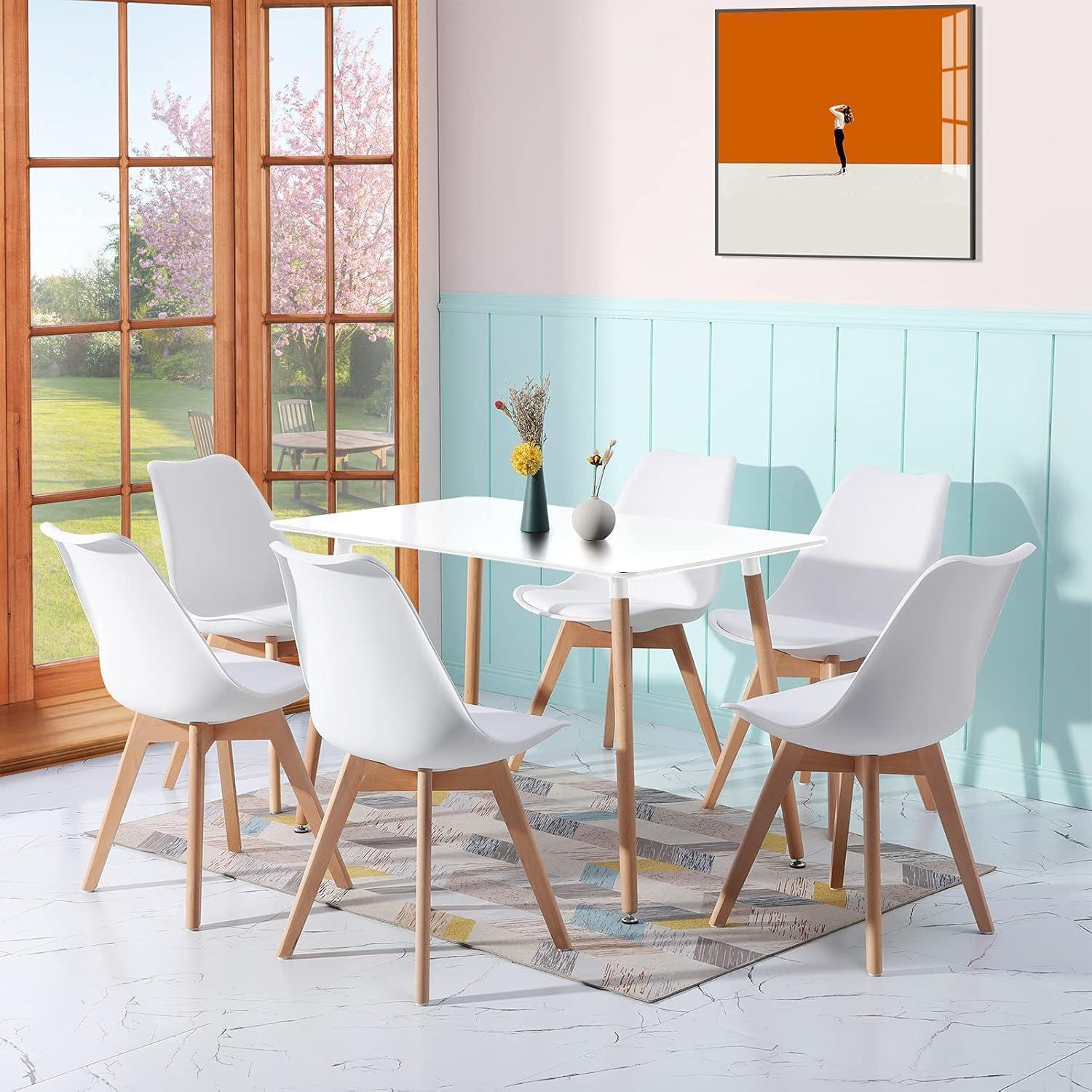 Un tavolo da pranzo bianco con sei sedie bianche si trova su un tappeto in una stanza luminosa con boiserie azzurra.