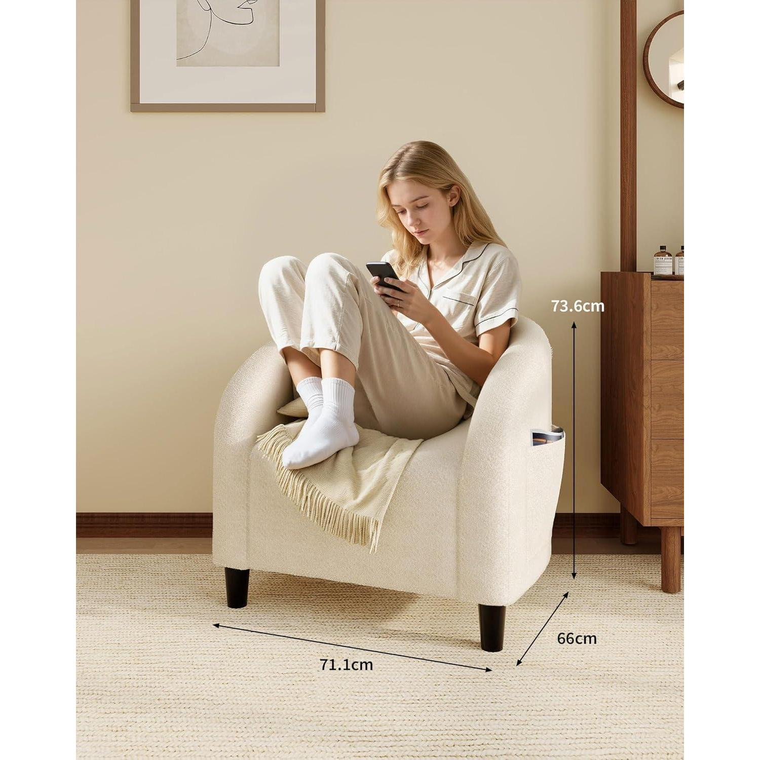 Una donna bionda con abiti chiari è seduta su una poltrona beige, guardando lo smartphone.