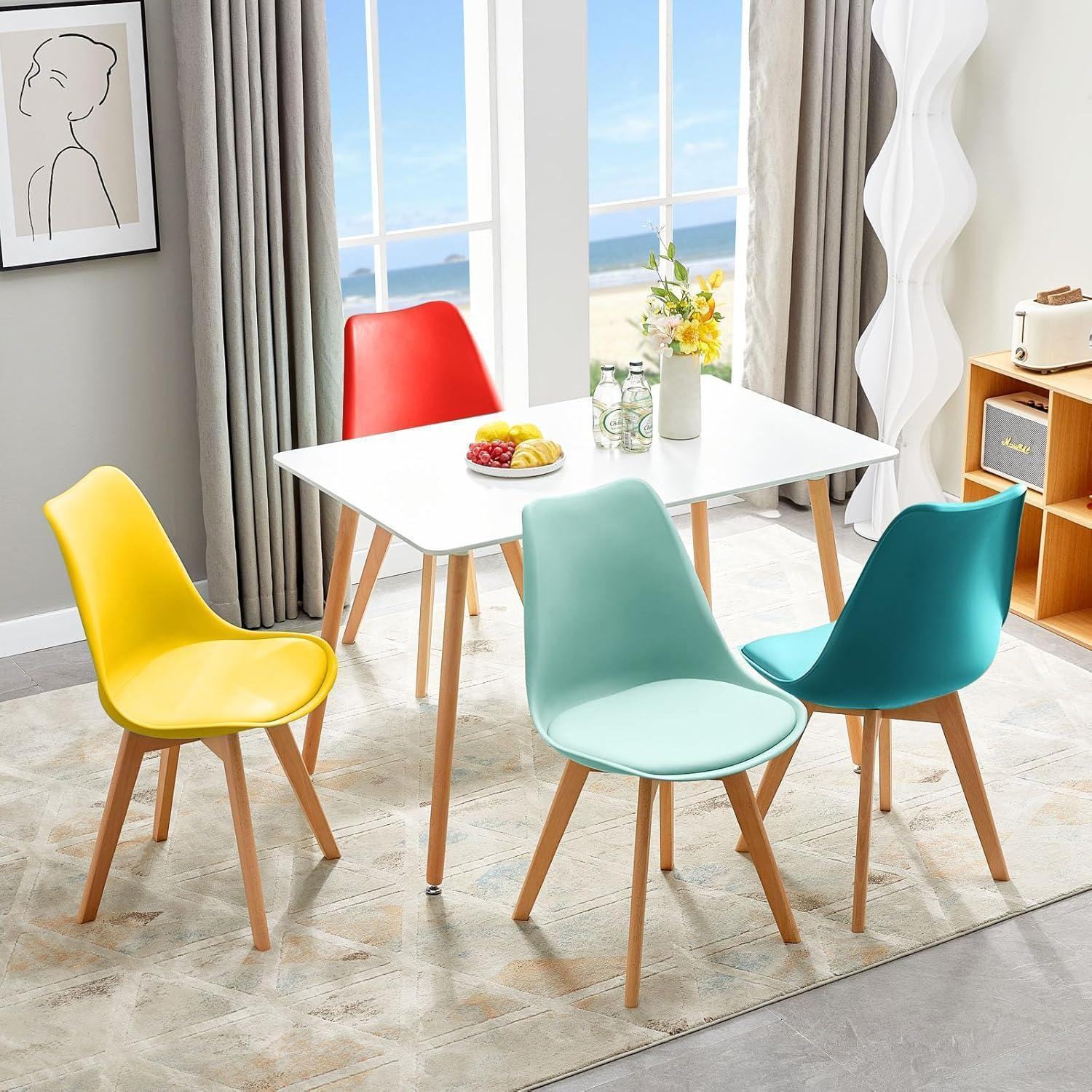 Una luminosa sala da pranzo con tavolo bianco e sedie colorate gialle, rosse, verde menta e blu.