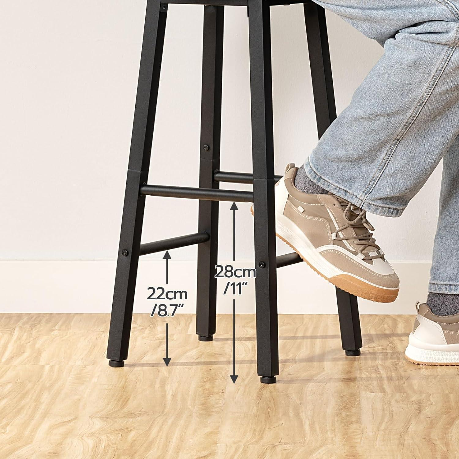 Una persona siede su uno sgabello nero, con poggiapiedi che mostrano misure di 22 cm e 28 cm.