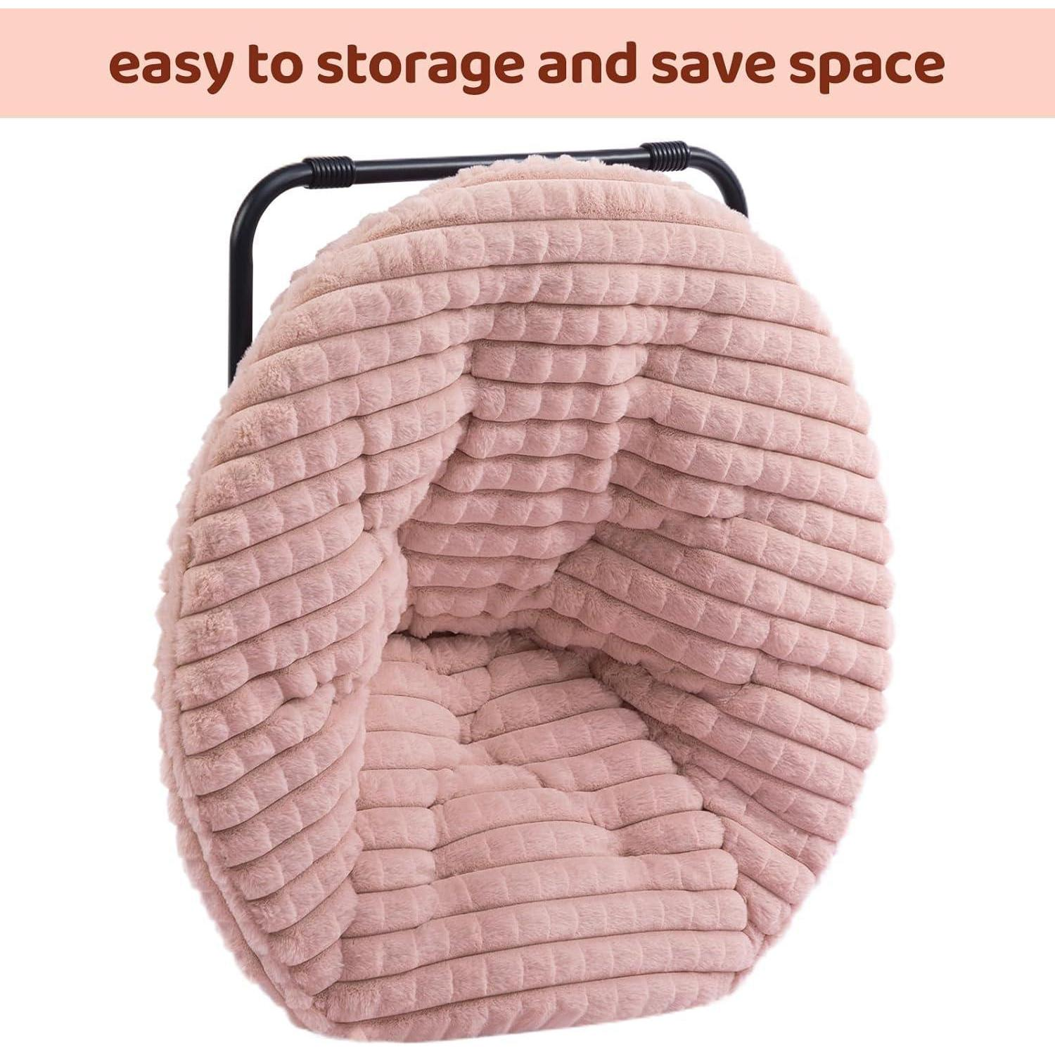 Una sedia a piatto in peluche rosa piegata con telaio in metallo nero su sfondo bianco.