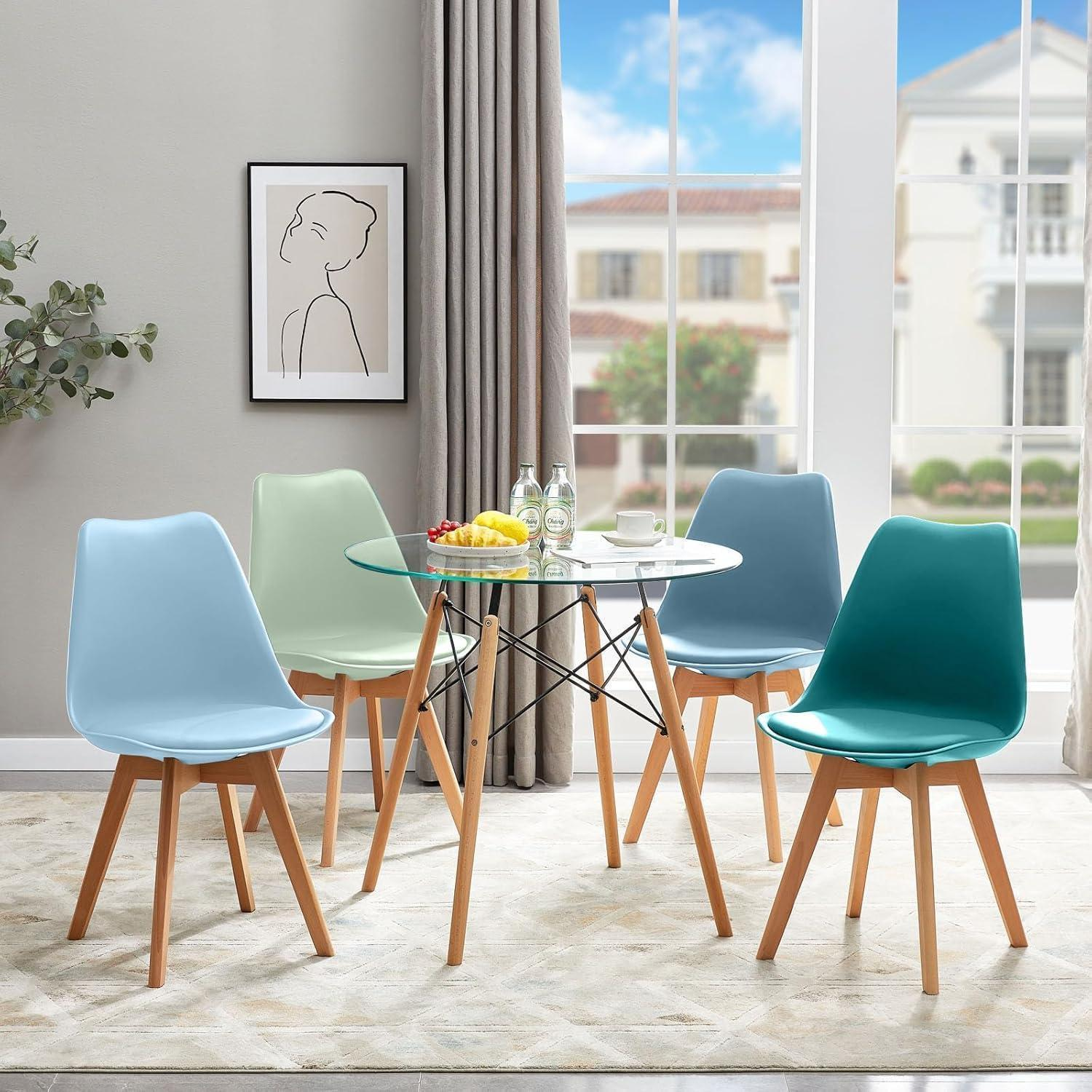 Un tavolo da pranzo in vetro con gambe in legno è circondato da quattro sedie colorate in una stanza luminosa.