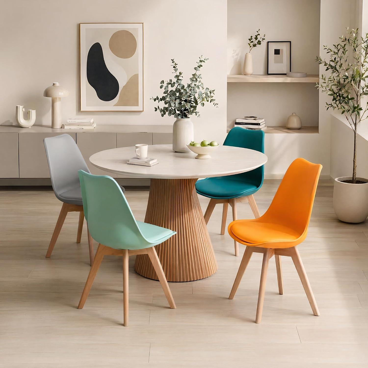Un tavolo da pranzo rotondo con base in legno scanalata è circondato da quattro sedie colorate in grigio, menta, ottanio e arancione.